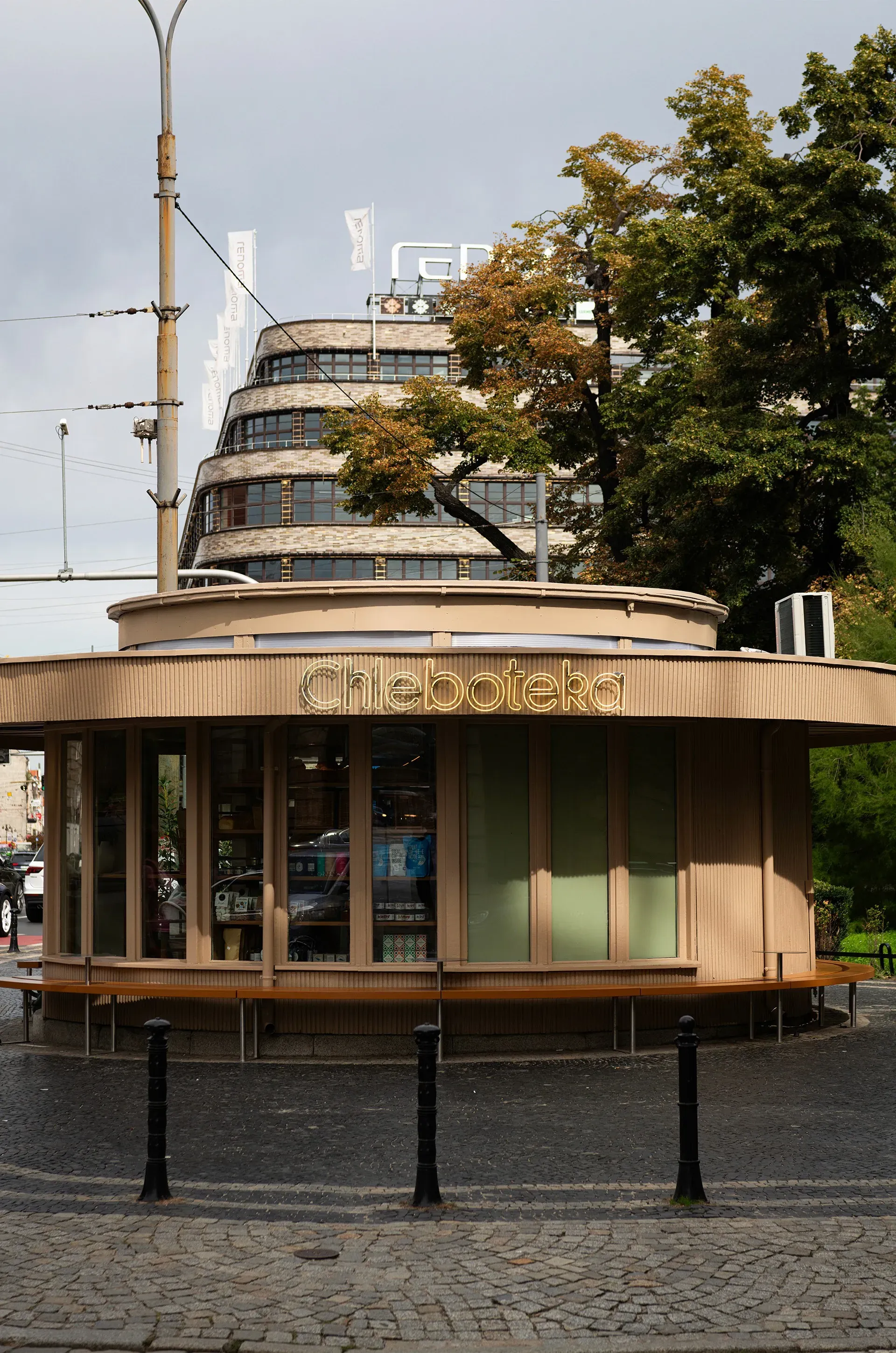 Round Chleboteka bakery pavilion with neon sign and orange bench in Wrocław, brand identity in architecture