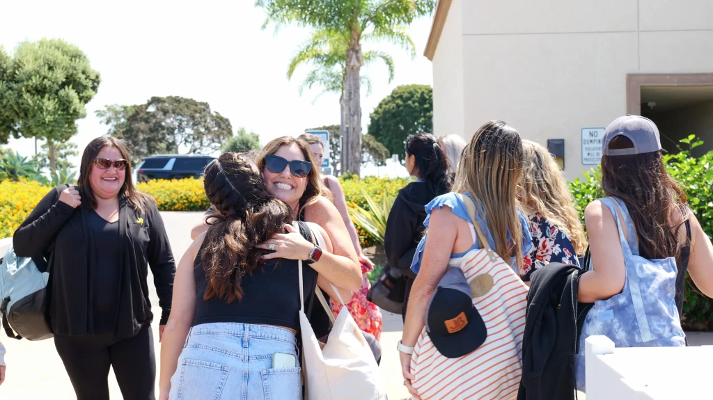 Office employees hugging happily at event