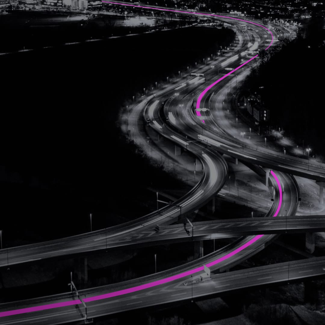 A busy highway at night with a route marked in pink