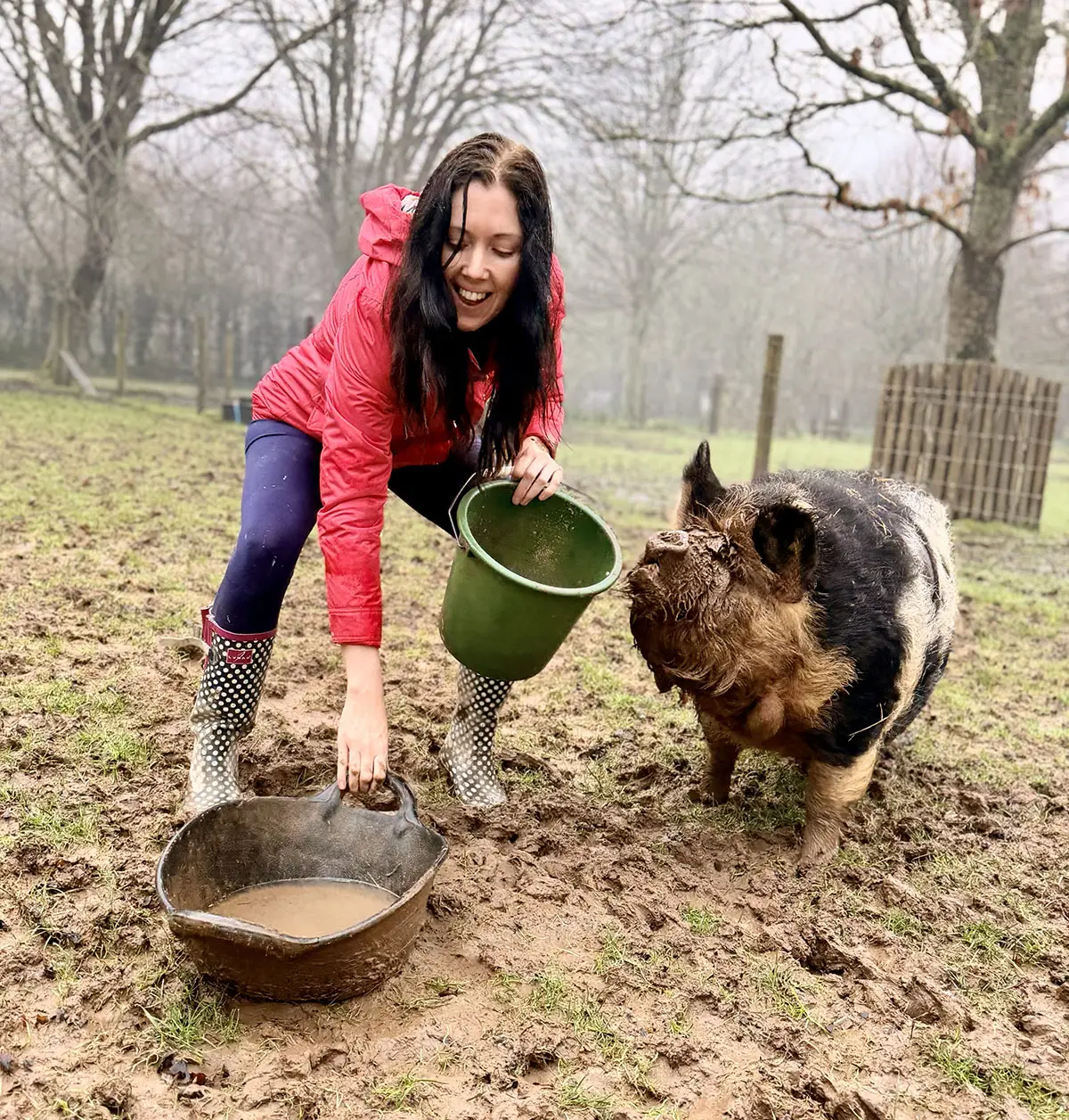 Zoë feeding friendly piggies in a muddy field at the Froomies farm in Cornwall