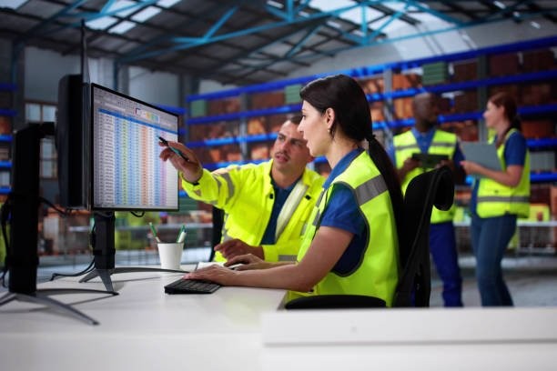 Image of people in high vis looking at a spreadsheet on a computer