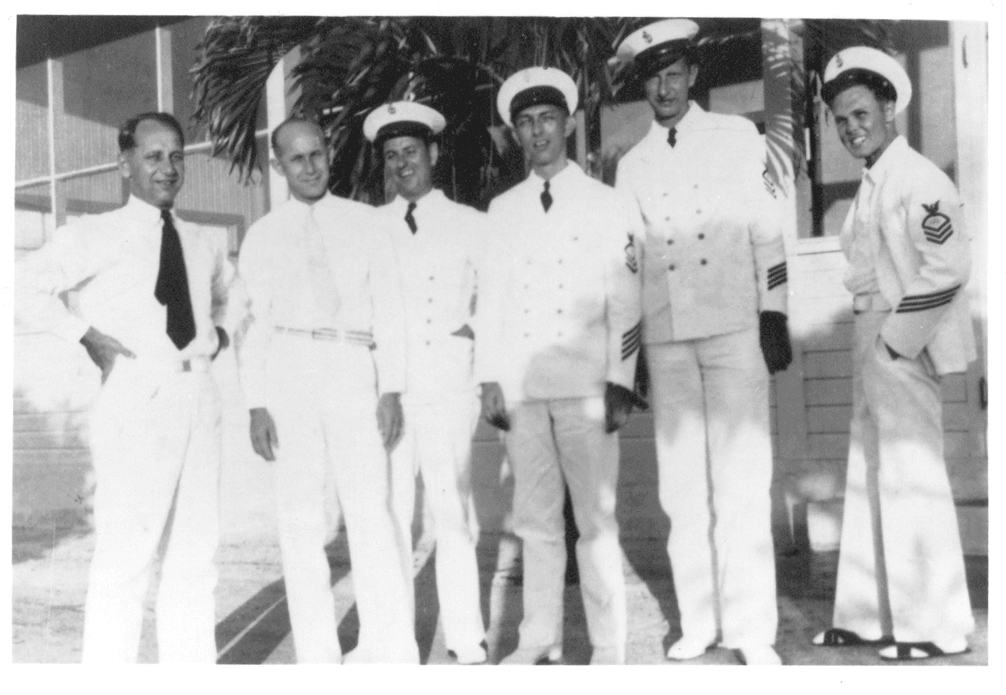 A group of men in white uniforms standing side by side, smiling and posing for the camera.