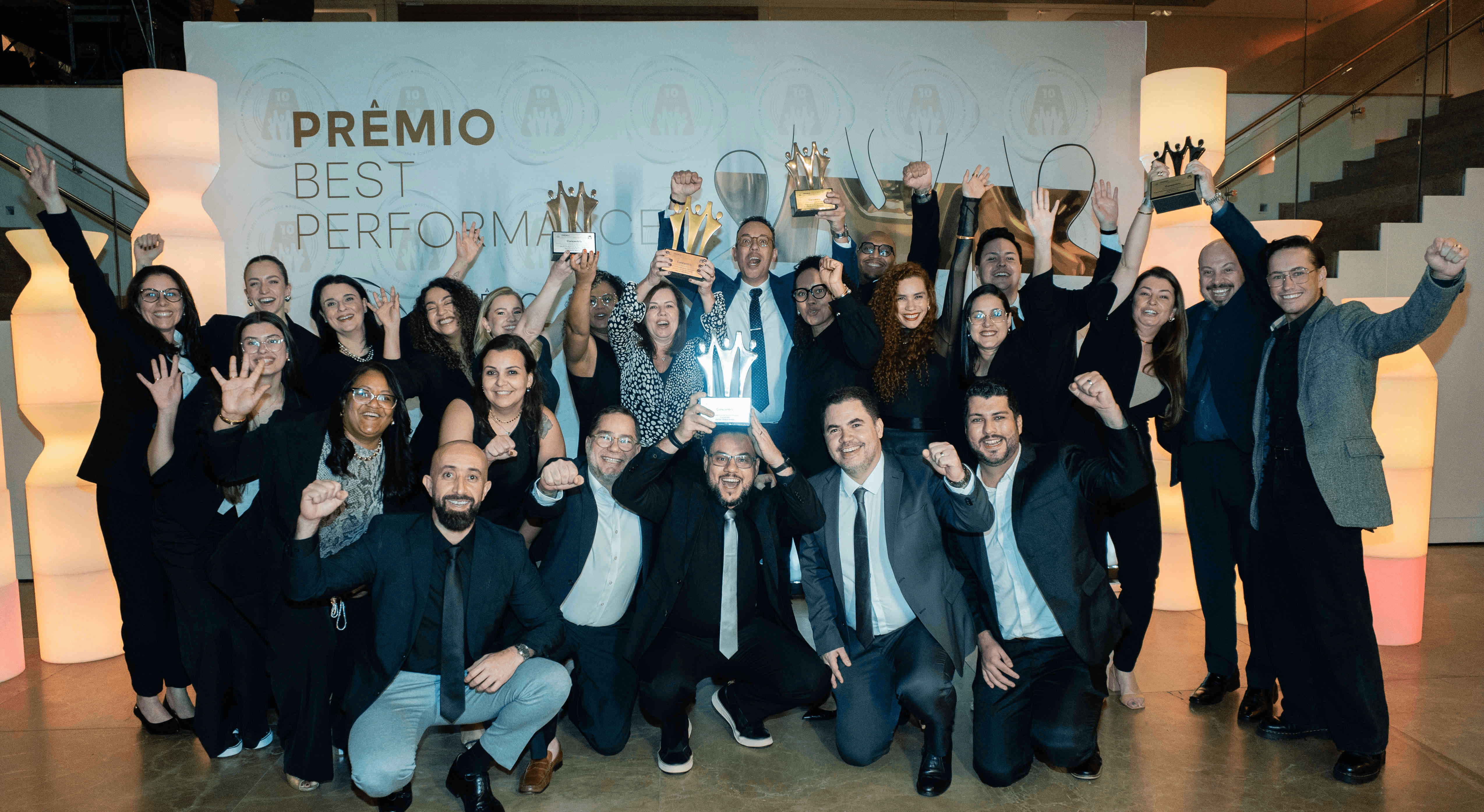 Executivos da Concentrix posando com troféu prata e certificado no palco do Prêmio Best Performance 2025