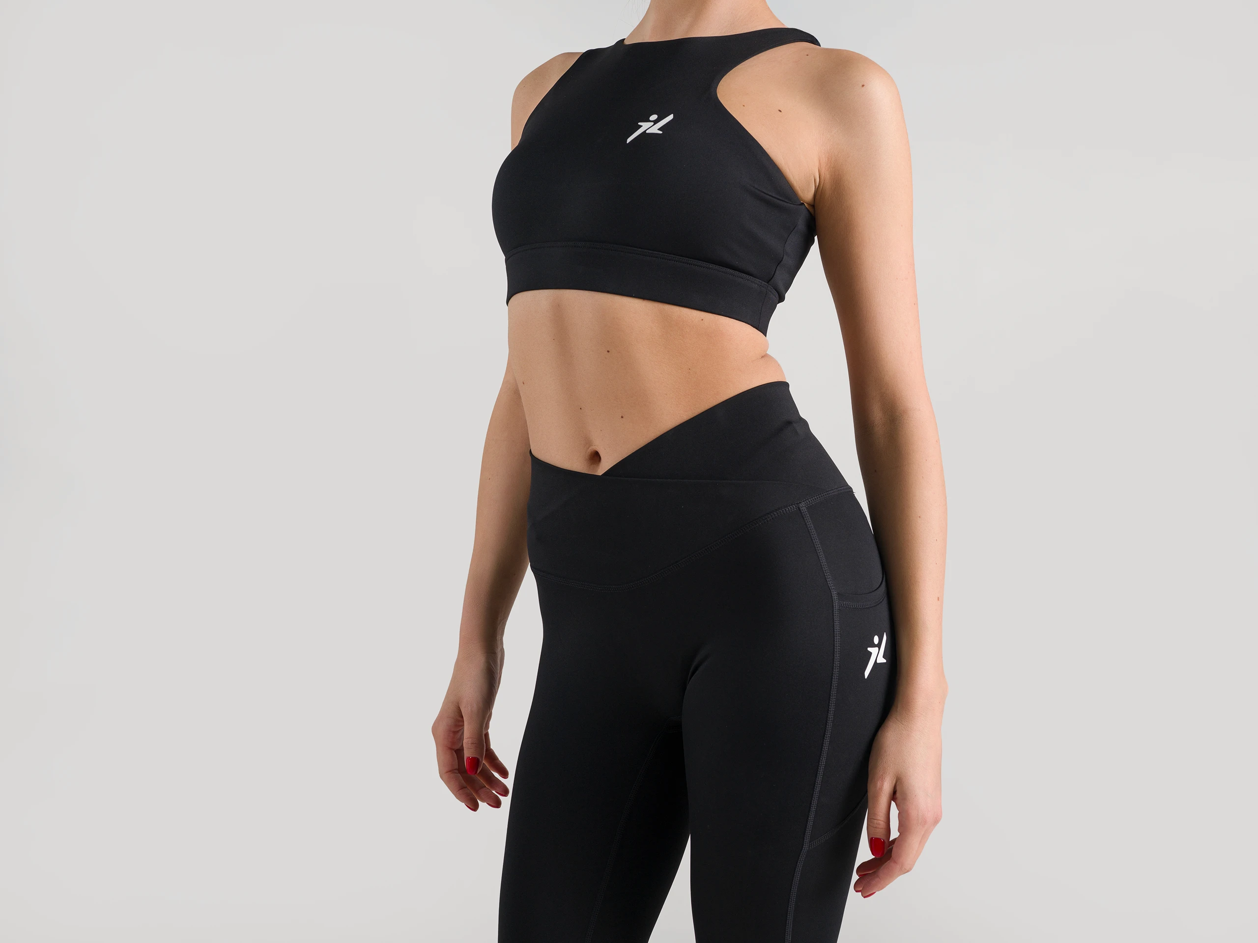 Strong, confident posture in black activewear, captured in a minimalist studio setting.