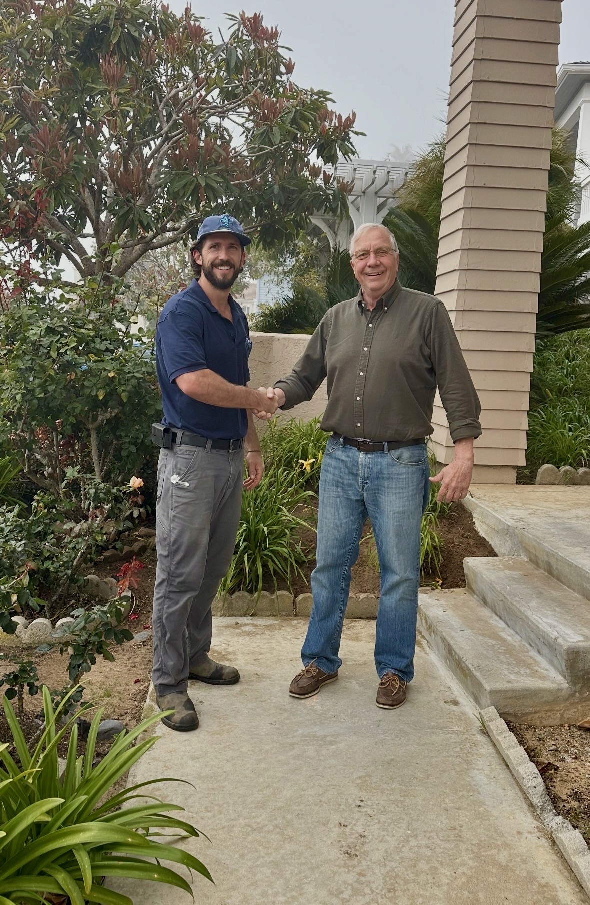 Owner Christian and customer Joe smiling in a front yard, representing a five-star service experience and successful sprinkler system repair.