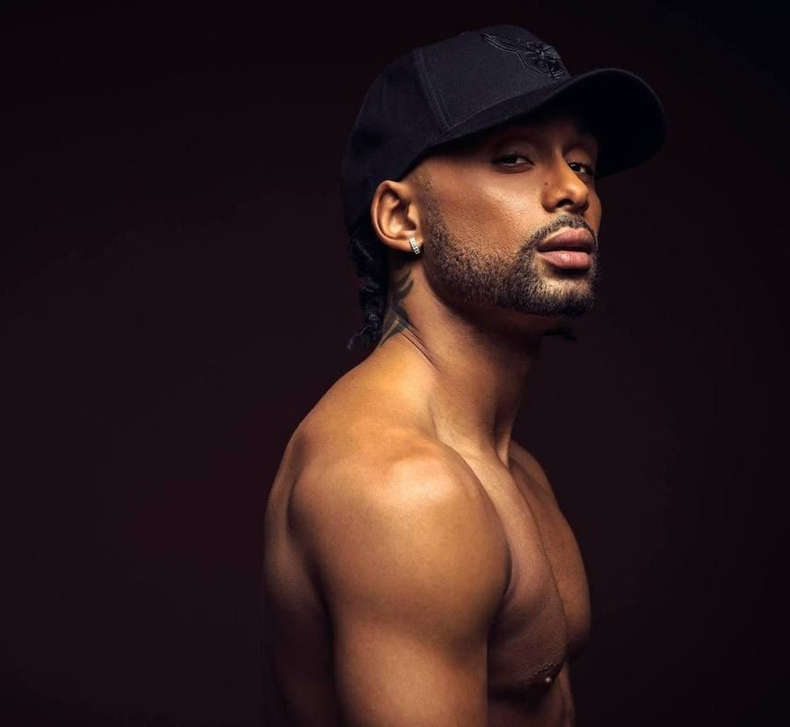 A glamorous cabaret performer with long hair, wearing an elegant white cutout dress, standing mysteriously by a dark piano under dramatic, cinematic slatted lighting
