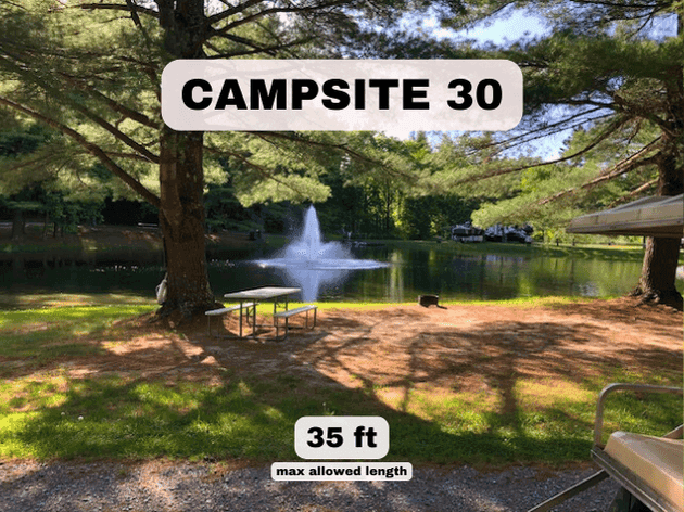 Campsite 30 at Pine Hollow Campground, a 35ft pondfront RV site with a picnic table and a view of the water fountain