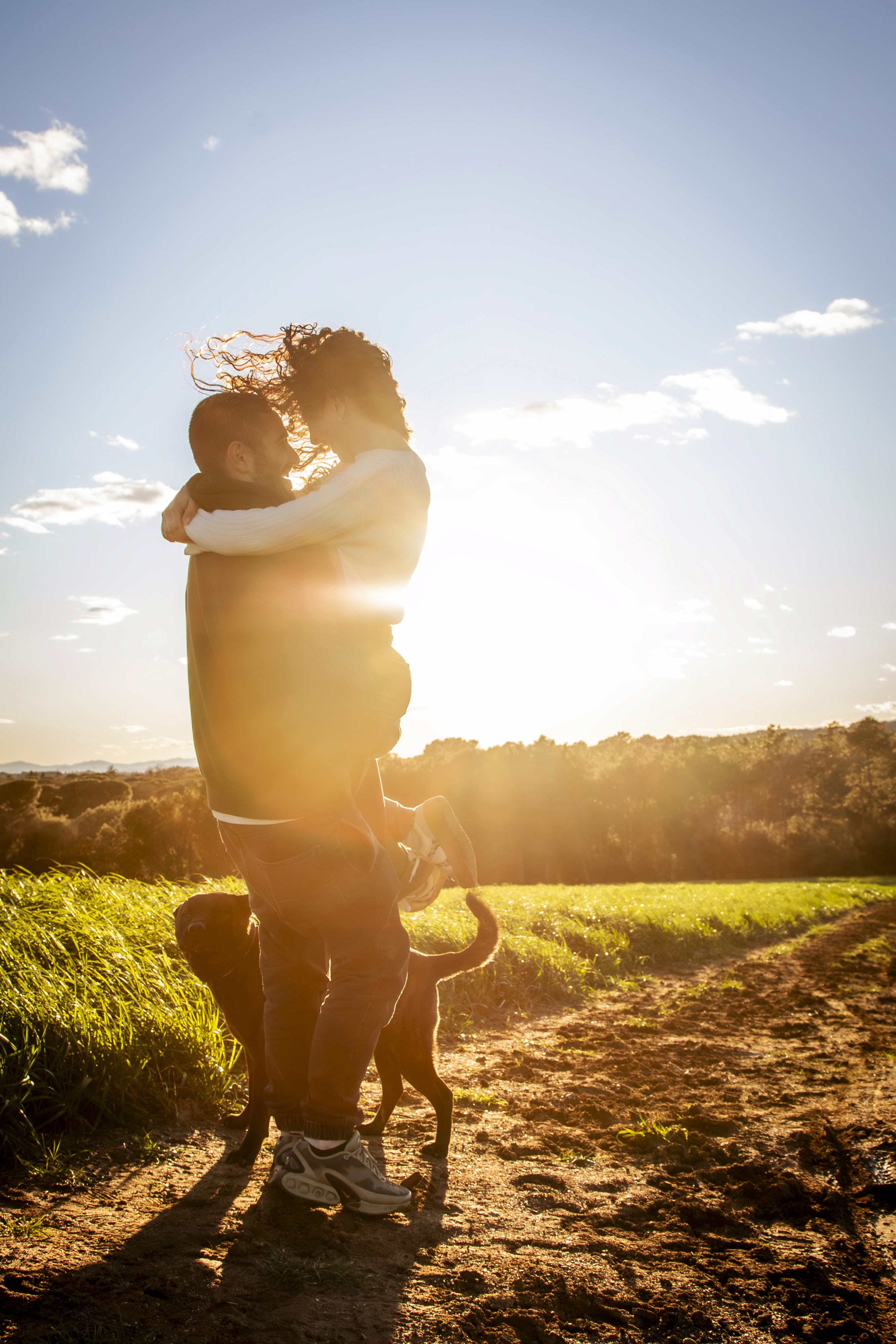 Pareja con su perro abrazados a la luz del sol