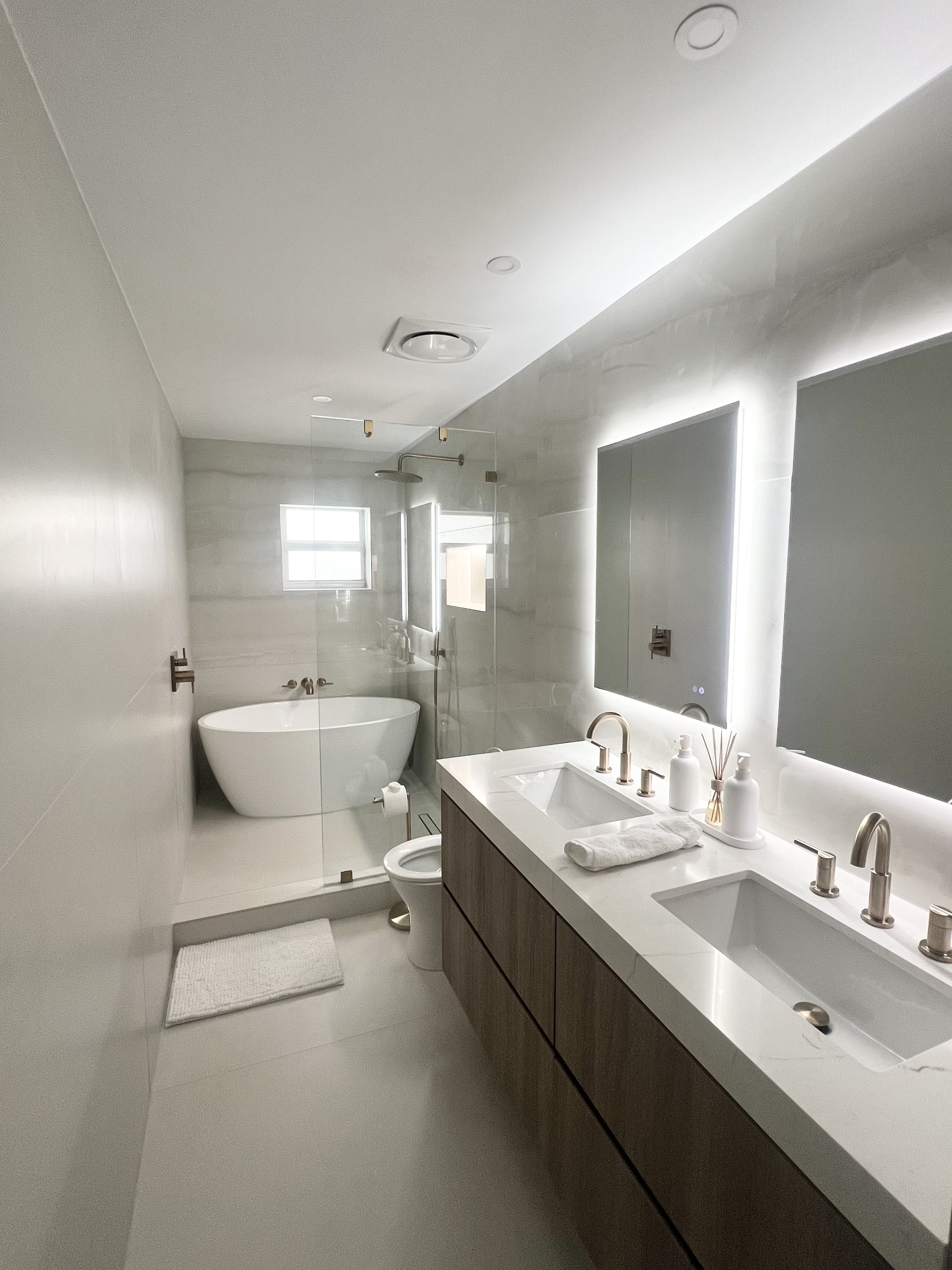 Modern bathroom with freestanding tub, double vanity, and backlit mirrors