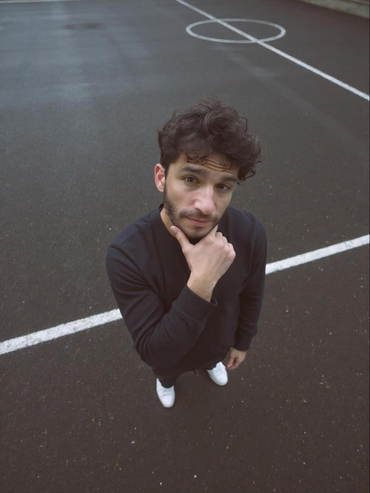 A thoughtful young person with dark hair gazes to the side, captured in soft black and white lighting.