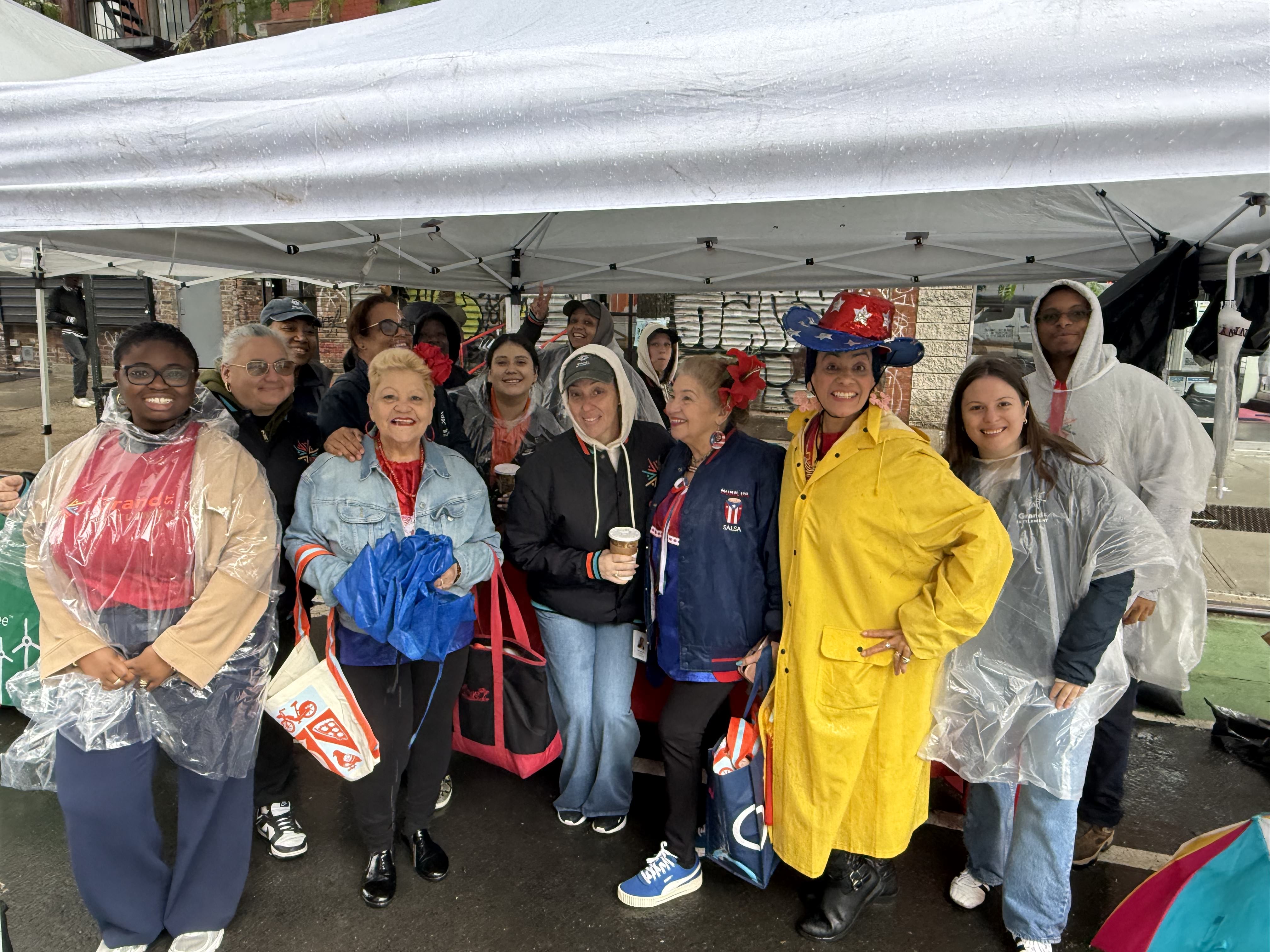 Staff and participants under a rain tent during an outdoor festival