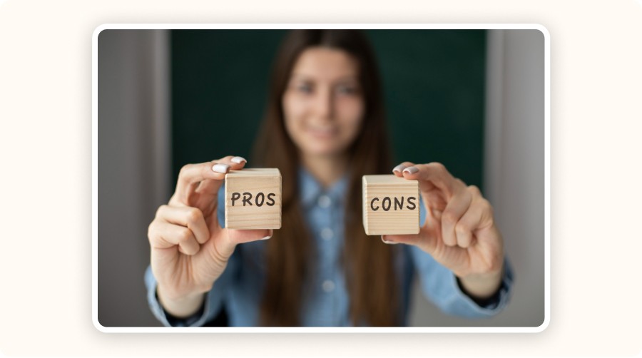 Woman holding two wooden blocks labeled “PROS” and “CONS,” representing strategic evaluation for small businesses.