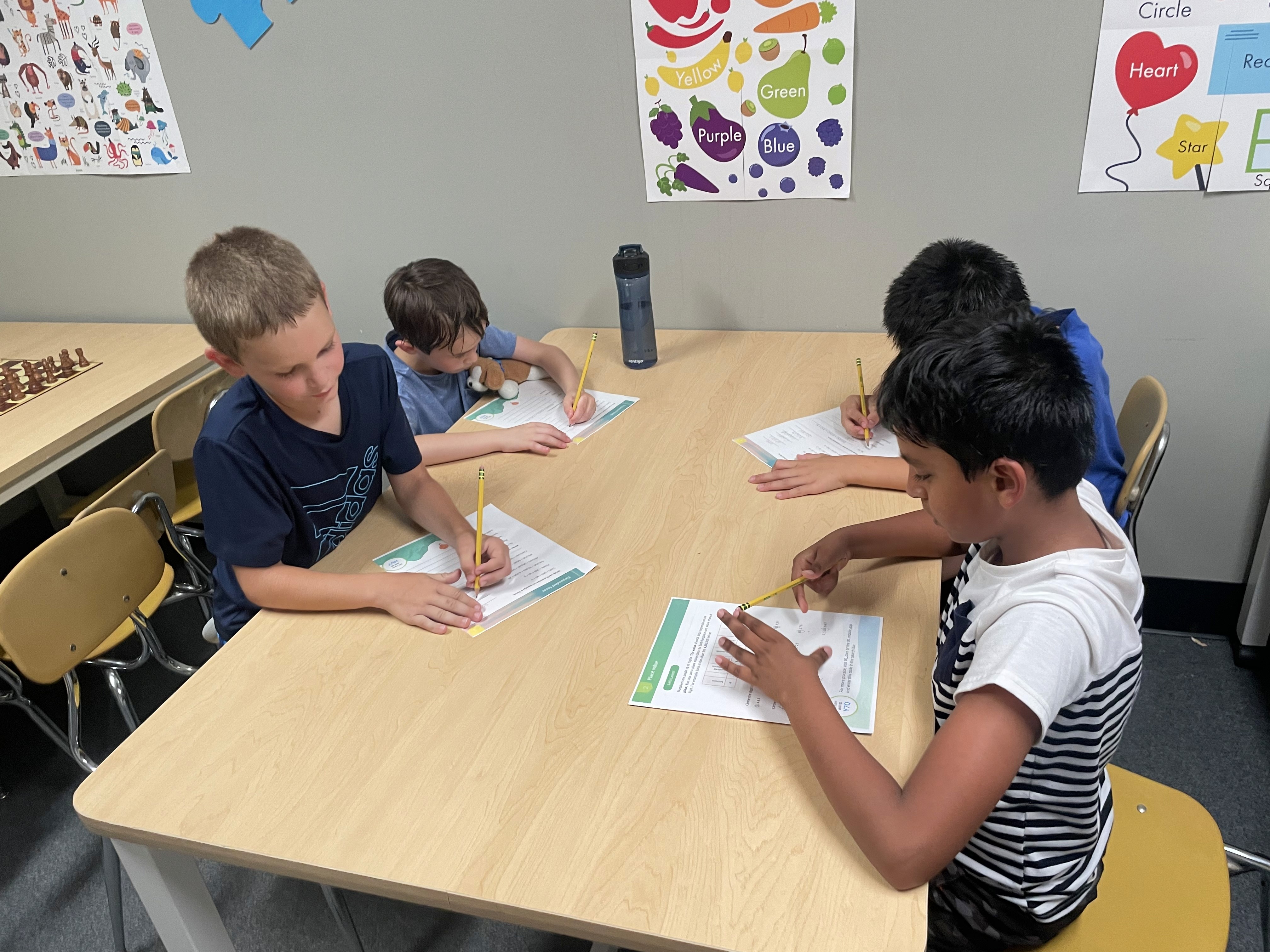 Four kids seated at a table working on problem-solving worksheets during a SportPlus Saturday Academy cognitive training session