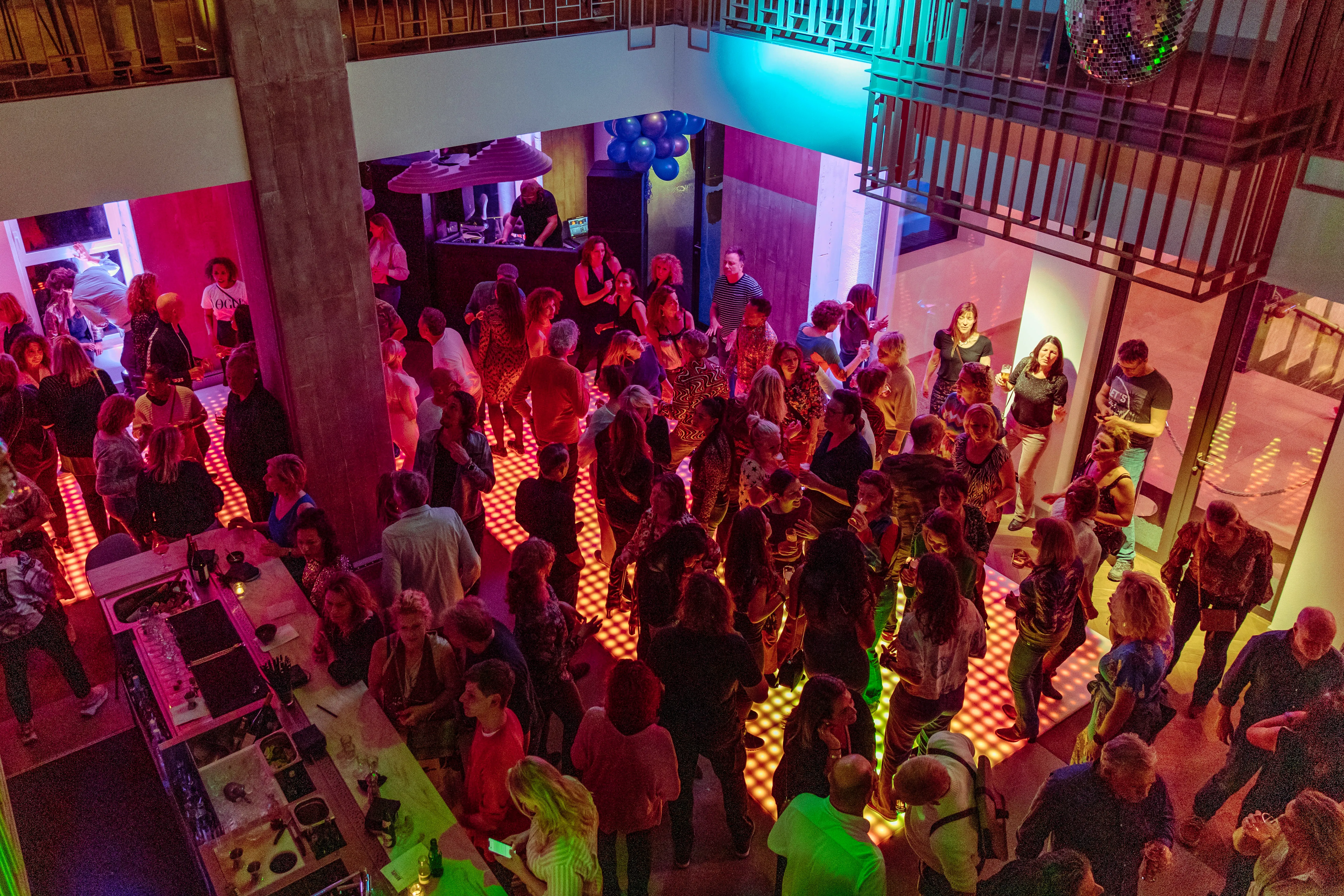 A vibrant party scene with colorful lights and a large crowd enjoying the atmosphere.