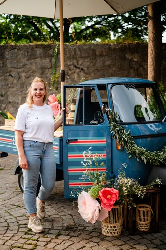 Freundliche Inhaberin der 'Giulietta', einer liebevoll restaurierten blauen Ape P 501 aus Himmelstadt, bereit für euer Hochzeits-Catering.