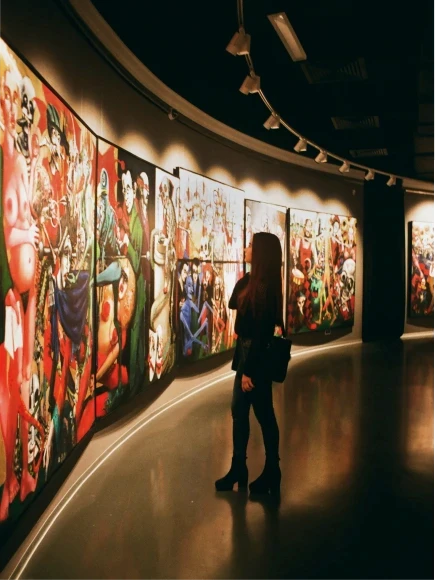 A person stands in a dimly lit art gallery