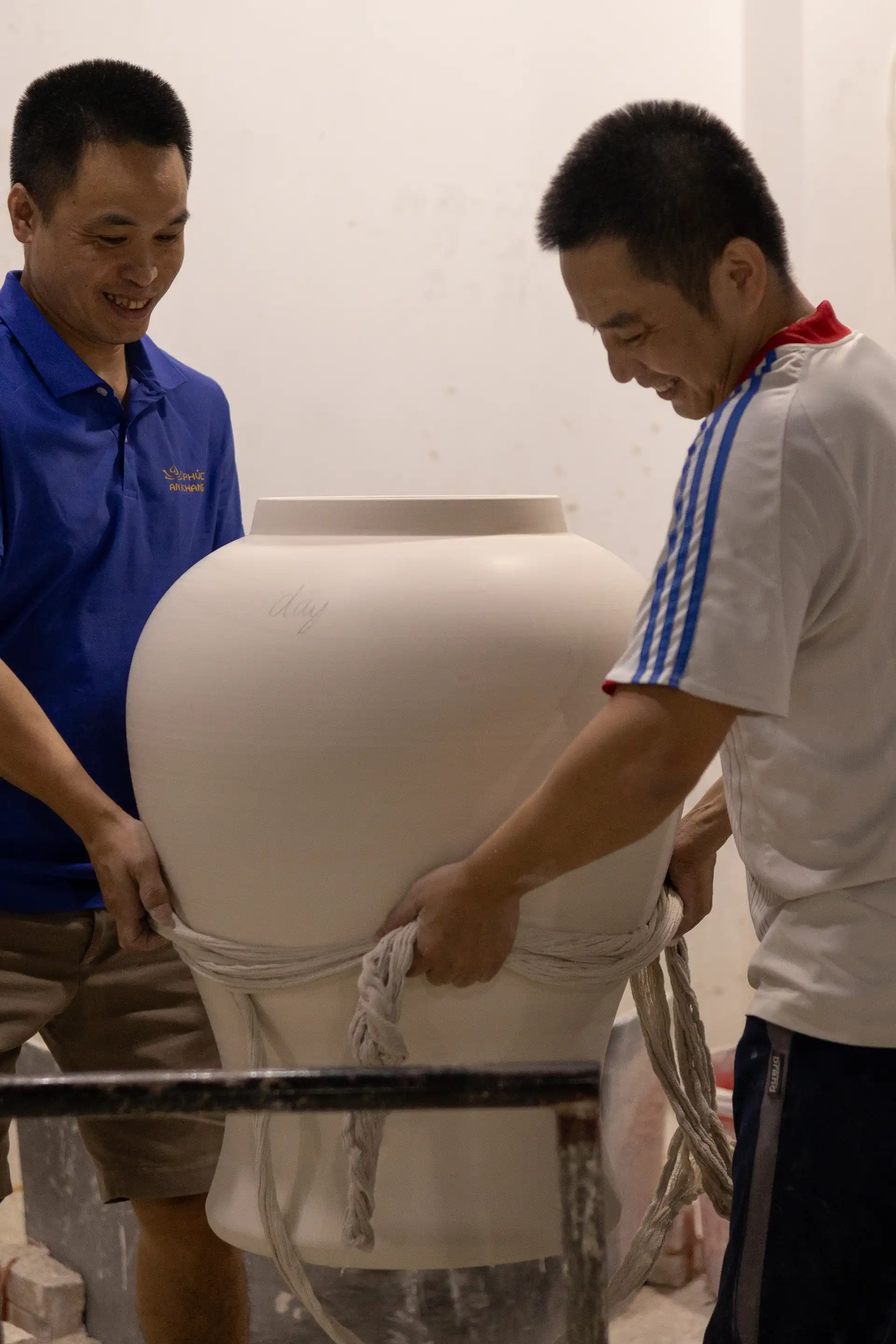 two people lifting a big ceramics vase