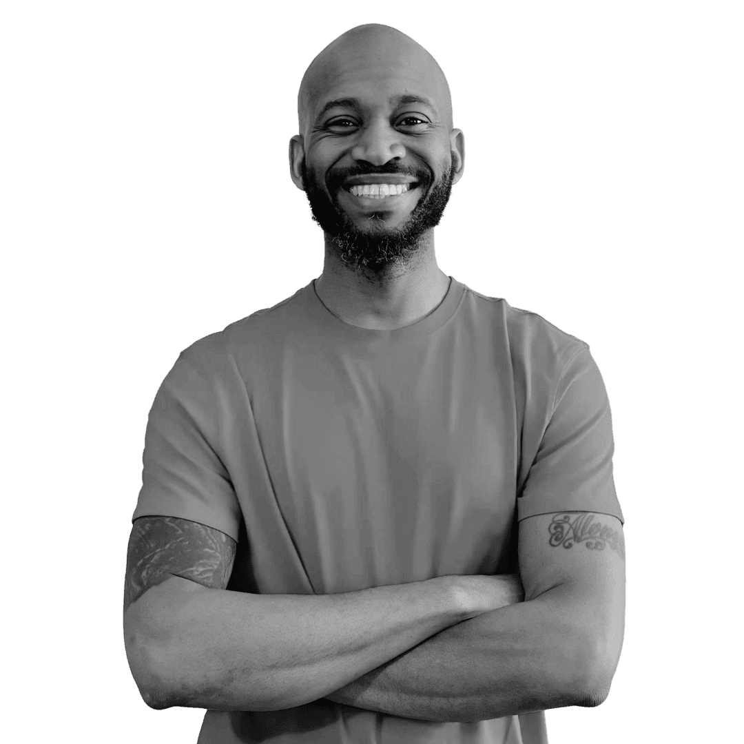 A relaxed woman wearing glasses and a beanie sits on a couch with a laptop, working in a cozy home setting with pillows and warm lighting.