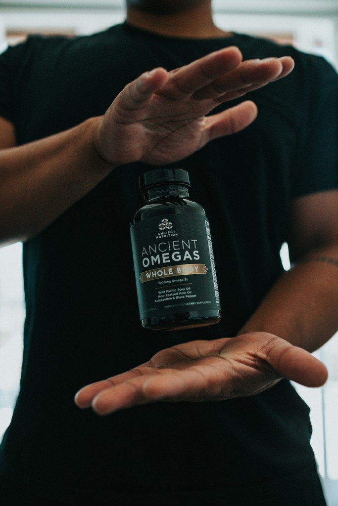 Person holding dietary supplement bottle representing health and wellness category