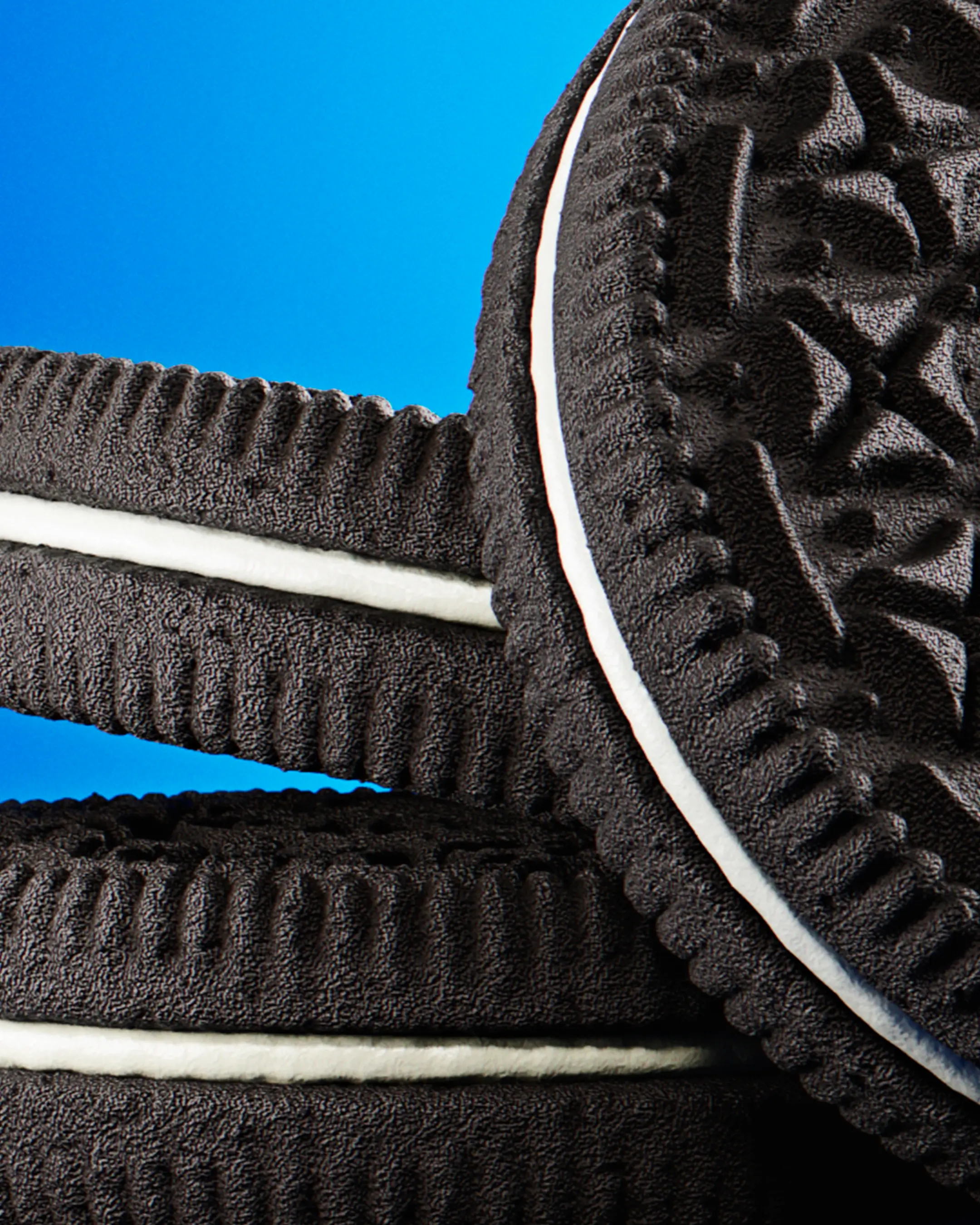 Close-up shot of a stack of 3D Oreo cookies, highlighting the contrast between the dark chocolate wafers and the smooth white cream filling.