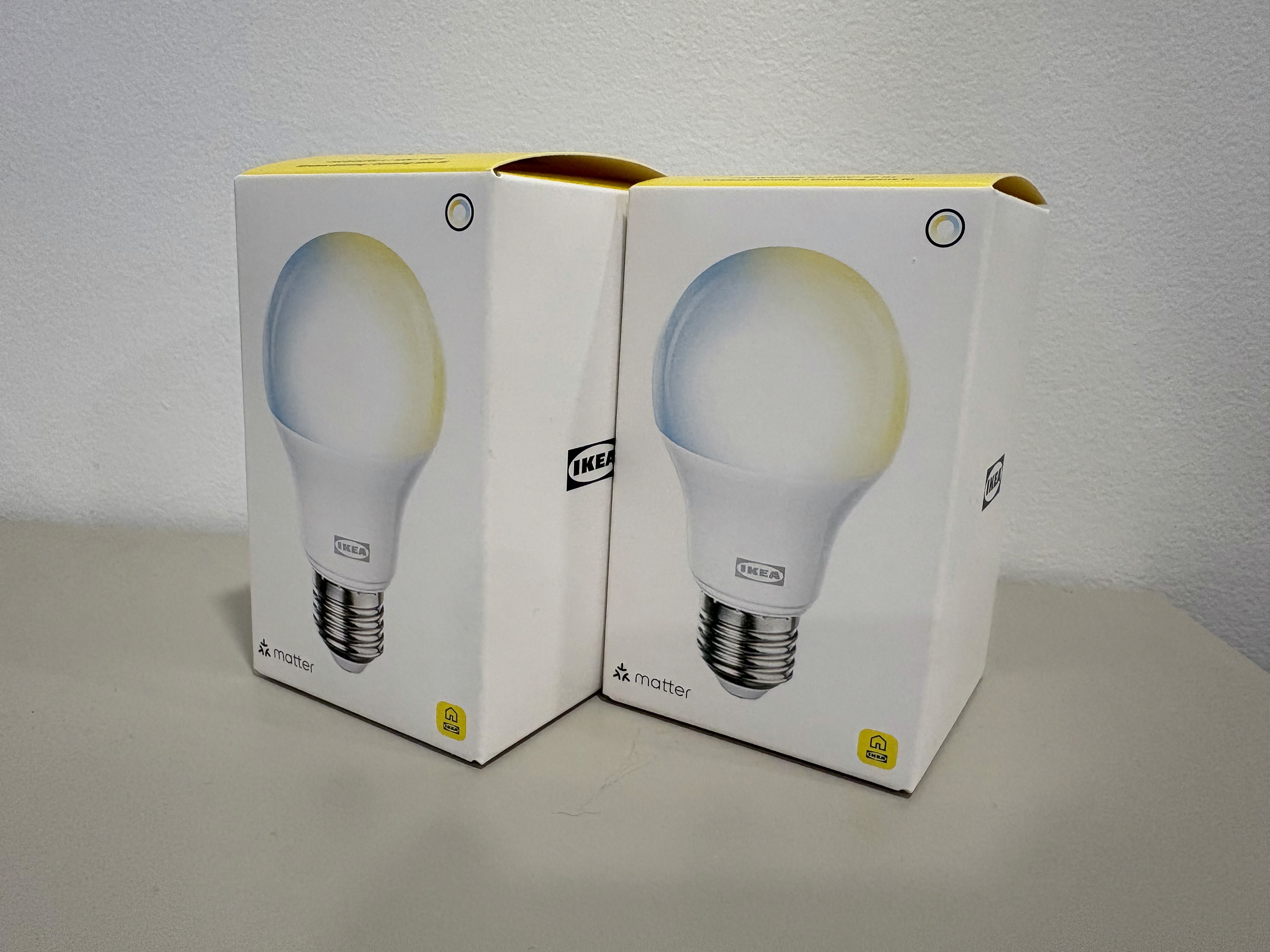 Two Ikea-branded LED light bulb boxes are placed side by side on a gray surface, featuring modern, energy-efficient lighting solutions.