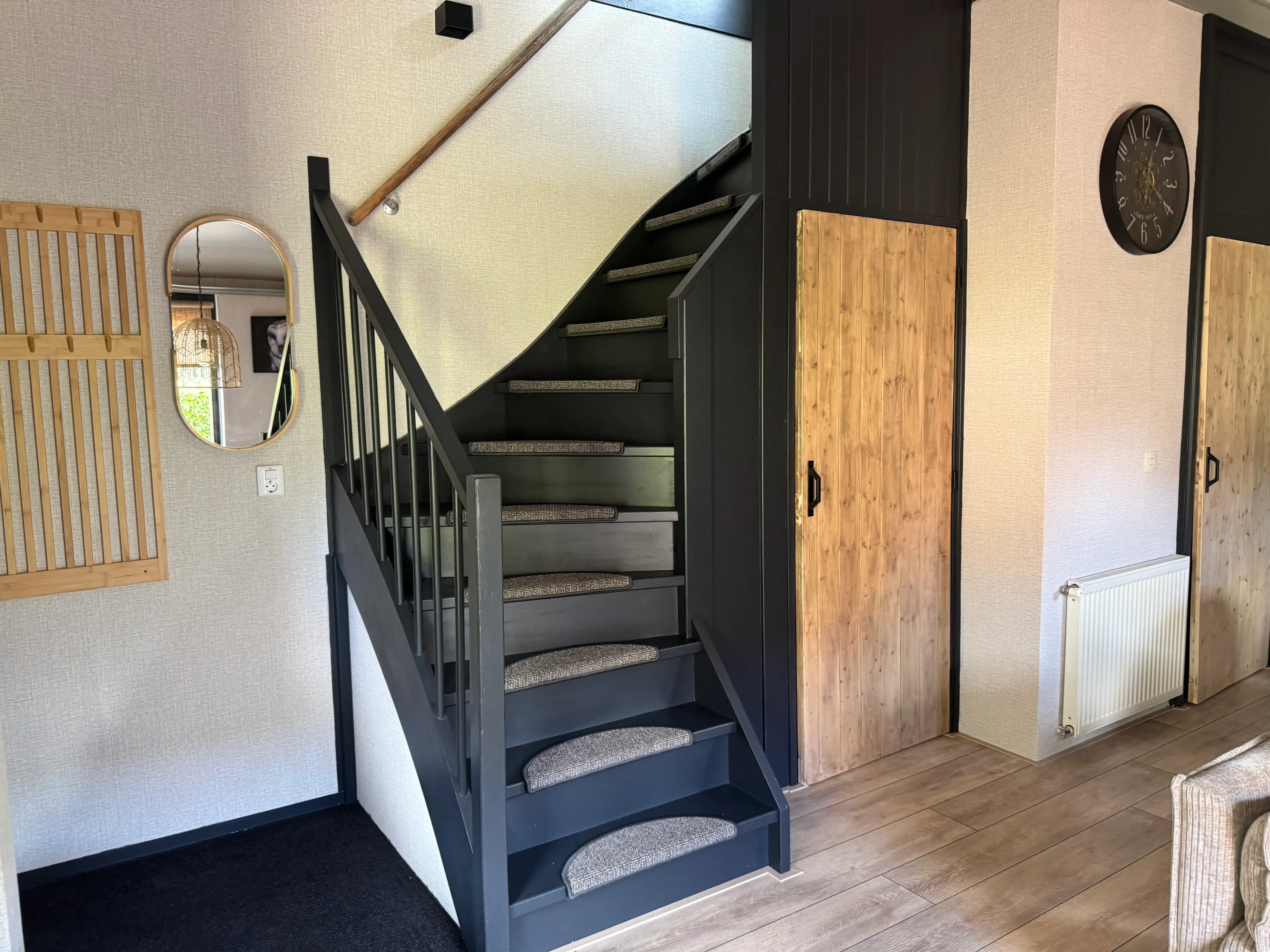 Zwarte houten trap naast houten schuifdeur in modern interieur.