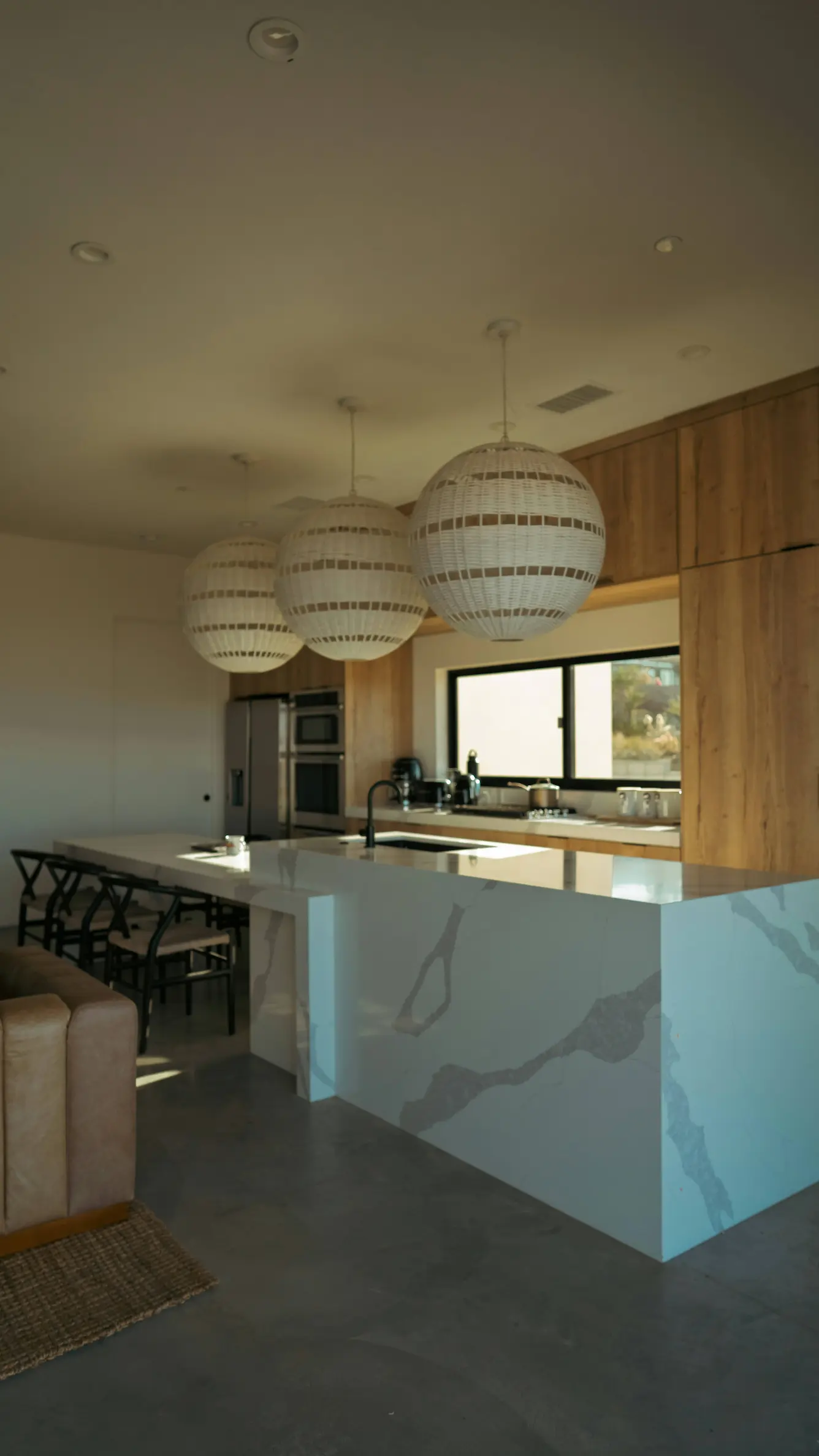 Kitchen with three ball lights hanging from the ceiling and yellow sunlight through the window