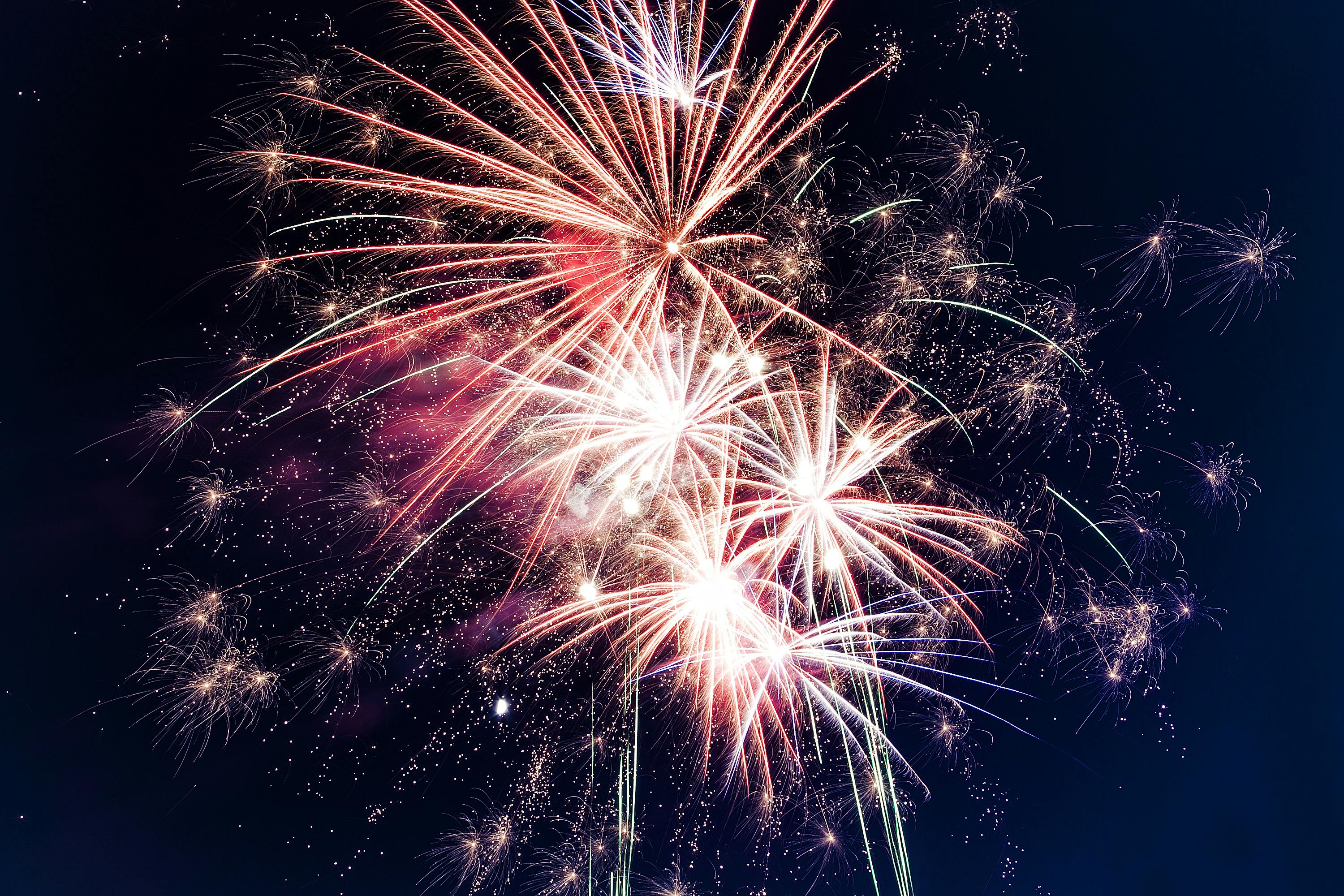 A vibrant display of 4th of July fireworks lighting up the night sky, featuring an array of colorful bursts in red, white, and gold