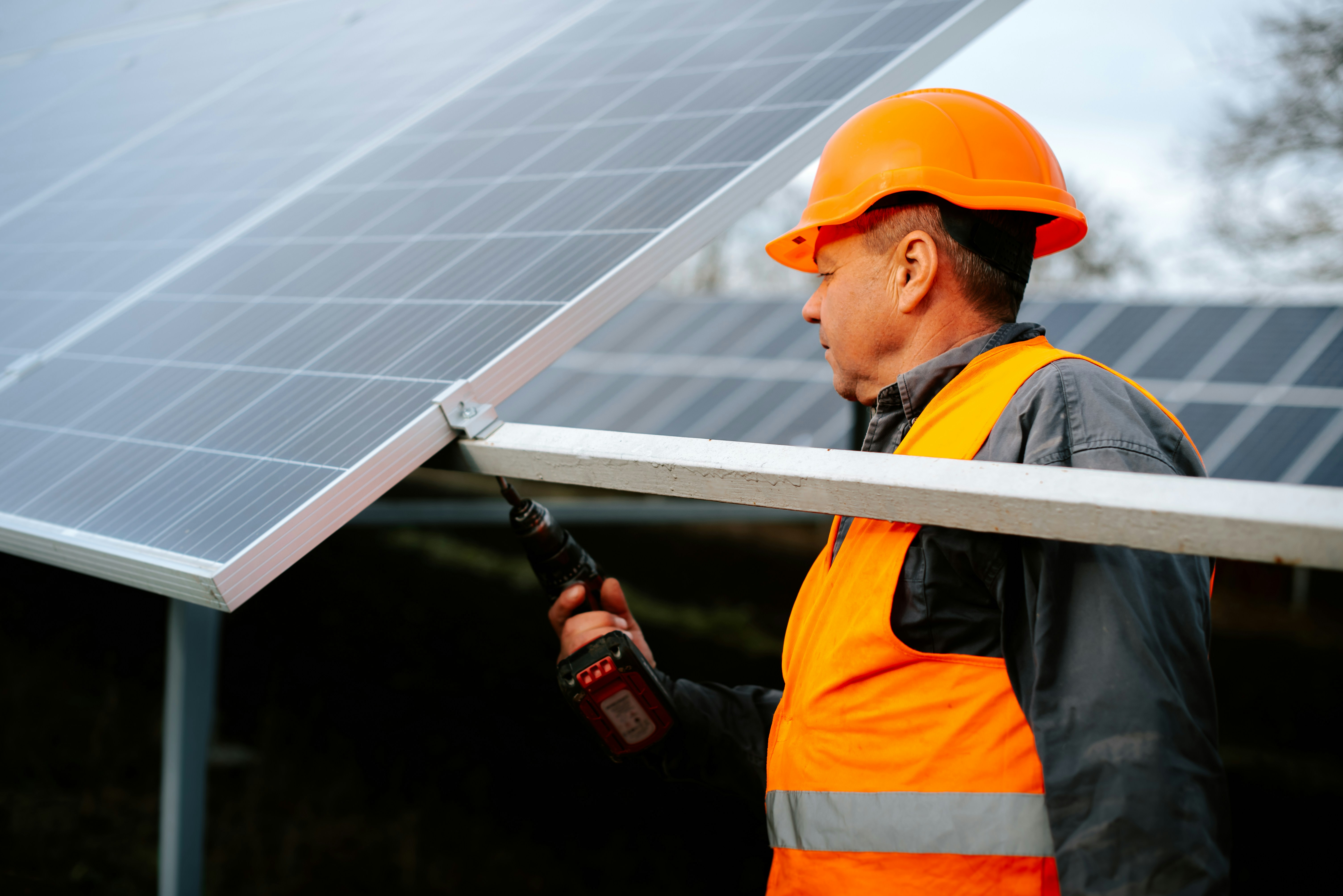 Worker installing solar panel with a drill
