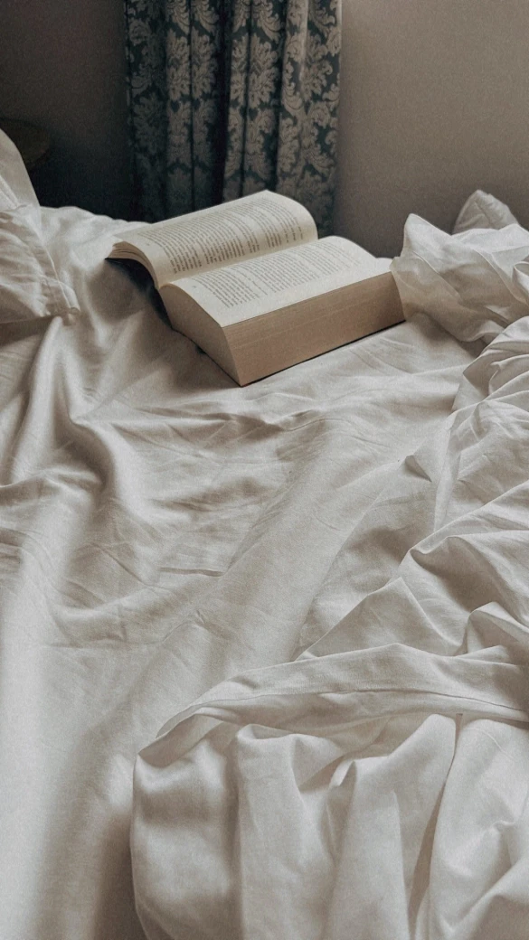 An open book on crumpled sheets; boudoir photography, Solothurn, Switzerland.