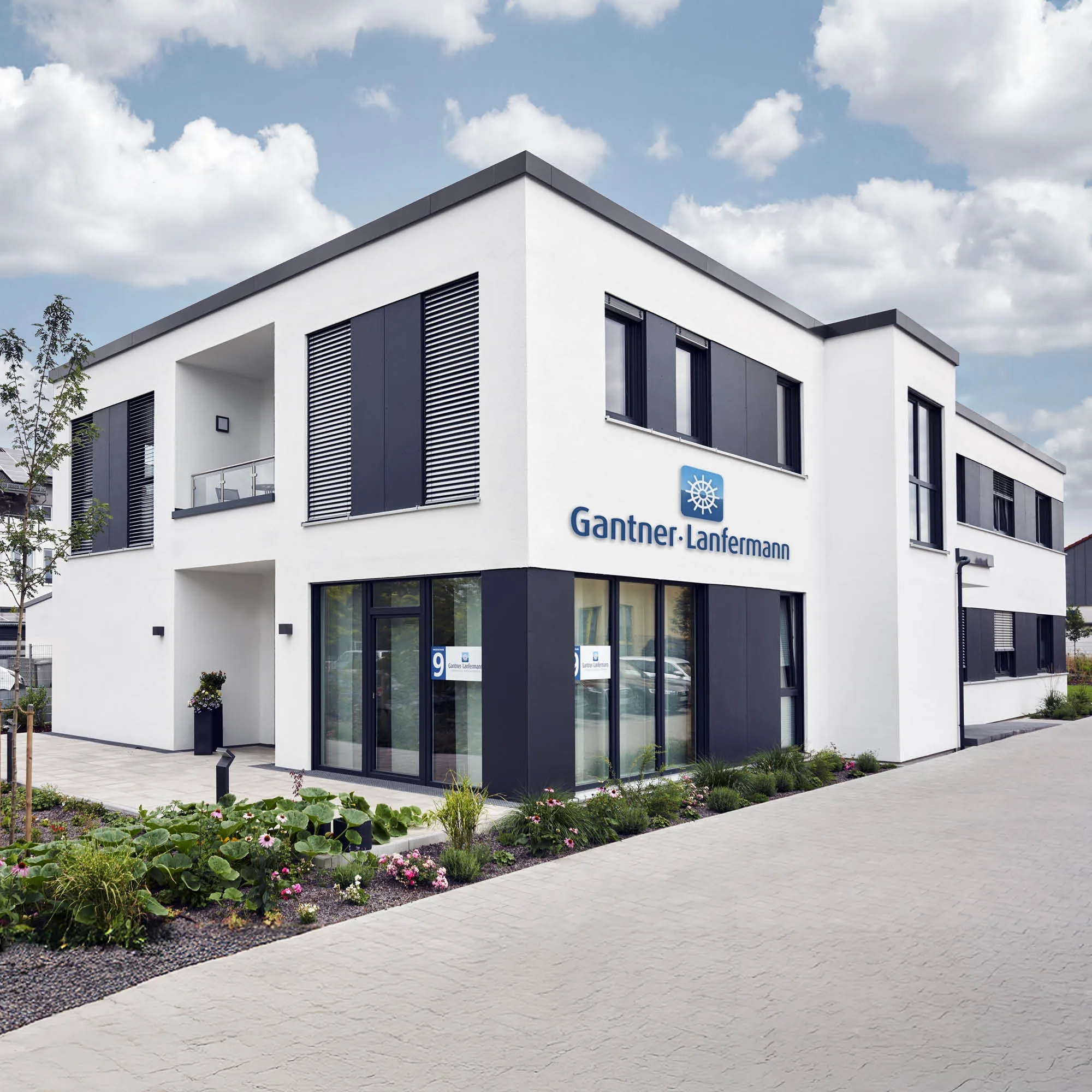 Modernes Bürogebäude in weiß und anthrazit mit dem Schriftzug "Gantner·Lanfermann" und einem Firmenlogo.