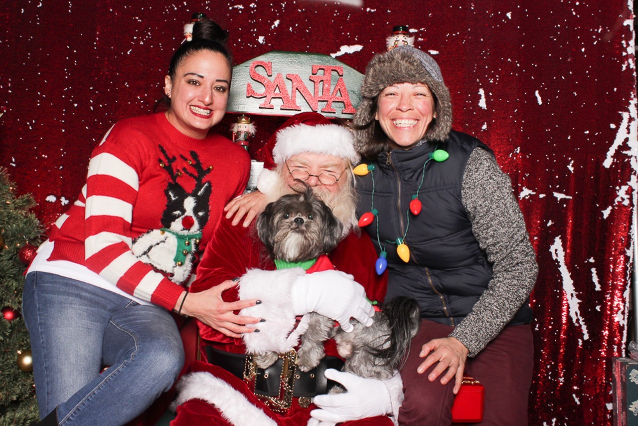 Two women with Santa Claus and a puppy.