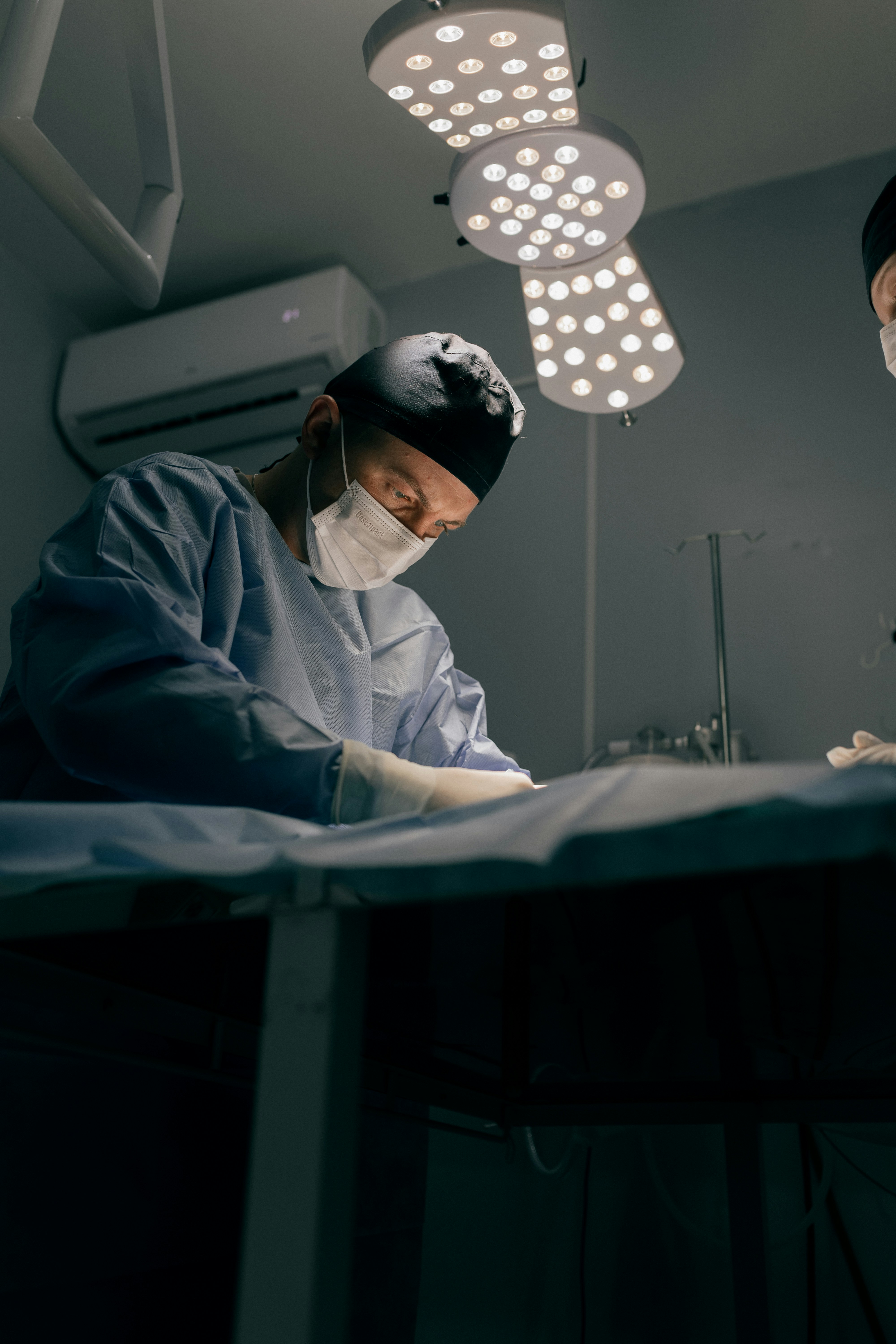 Surgeons in operating room with bright lights above.