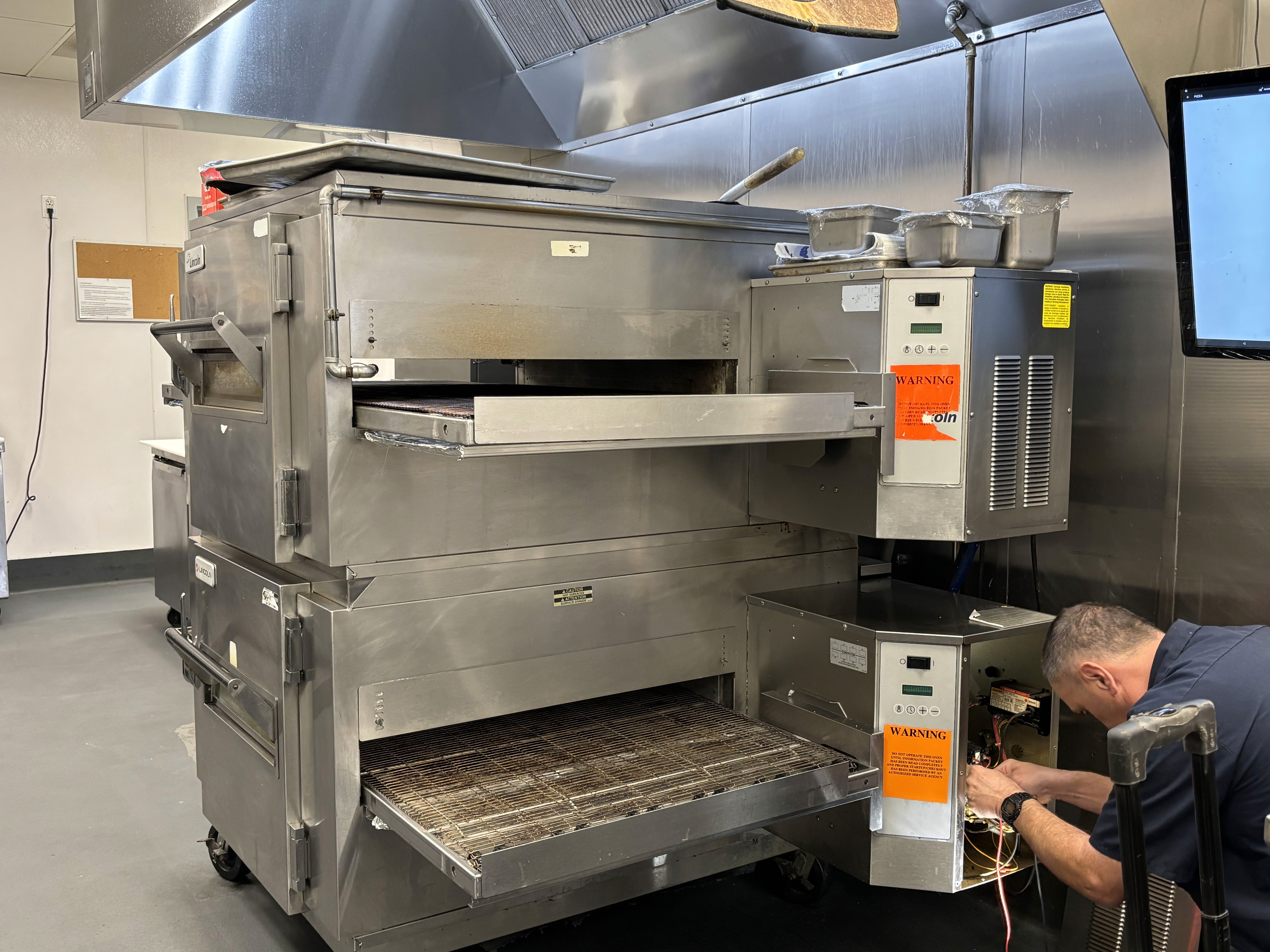 a man around 45-50 years old, dressed in a technician's uniform branded 'AngelSky', working in a traditional industrial kitchen