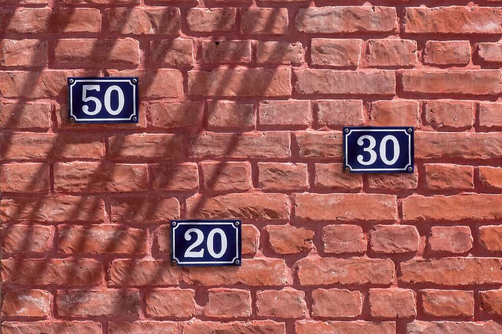 Números 50, 30 y 20 en una pared, asociados a la regla para ordenar tu plata