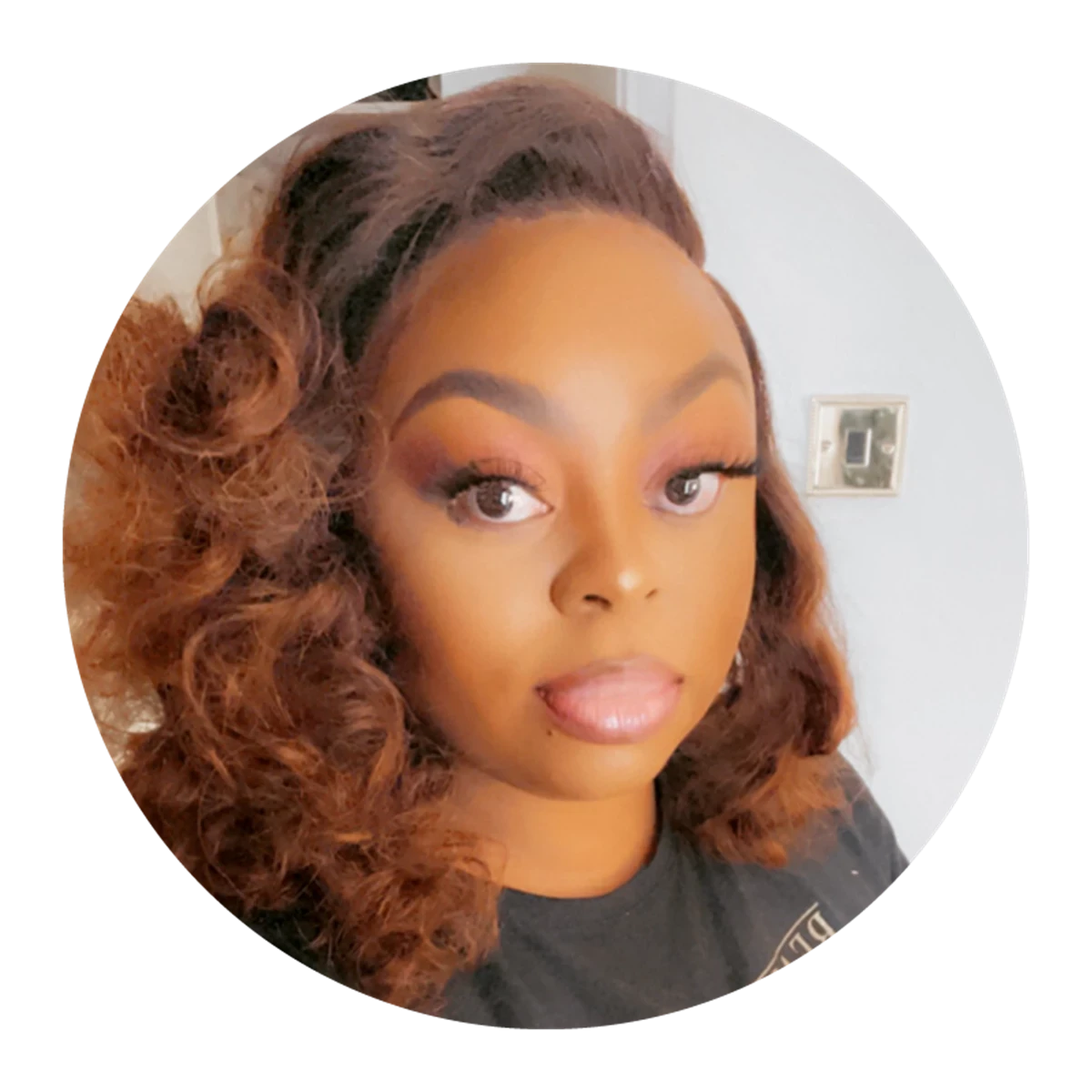 Person with voluminous curly hair wearing a dark t-shirt indoors.