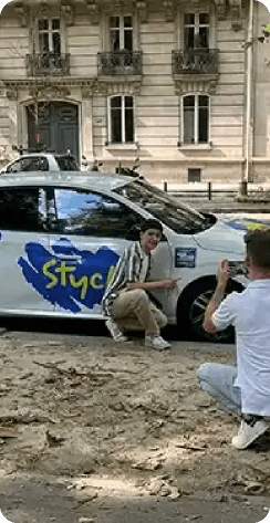 Photo d'un tournage avec une voiture, le fondateur et un acteur