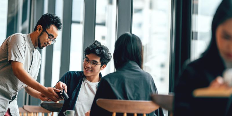 A male server serving a pair of customers in a restaurant