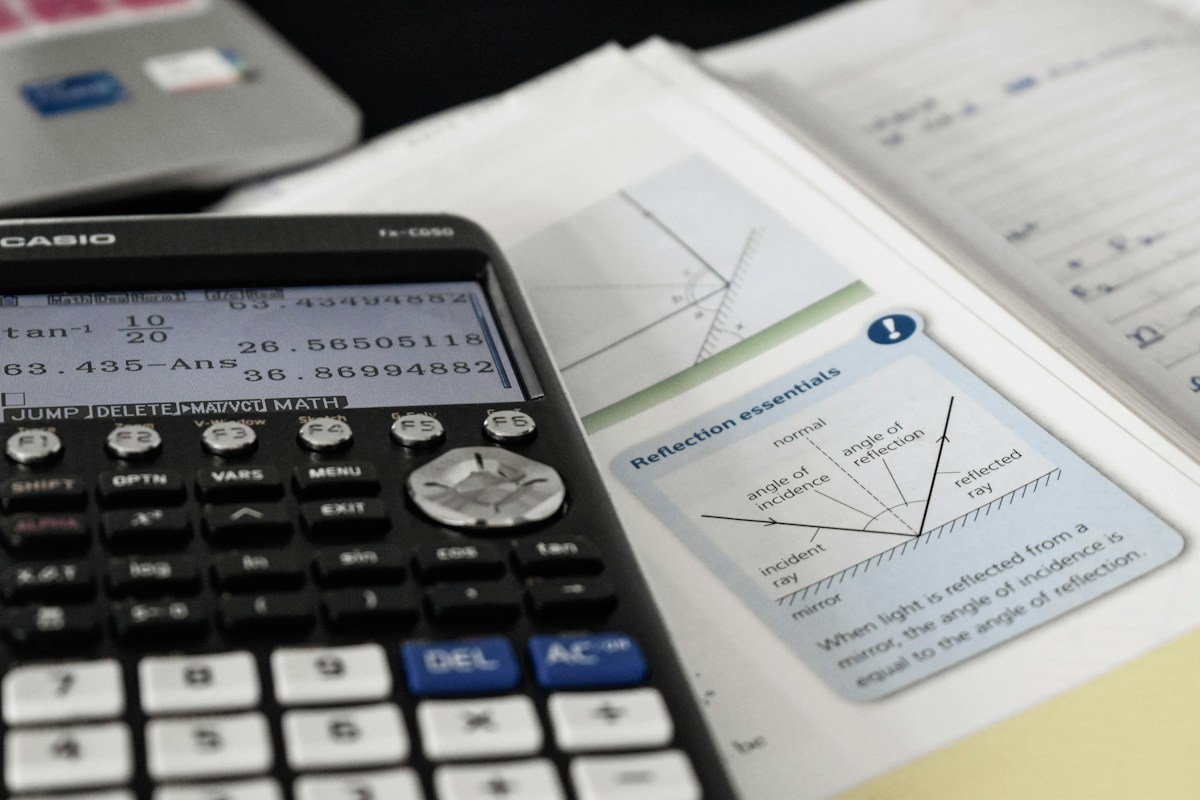 A scientific calculator on a maths textbook open at a graph