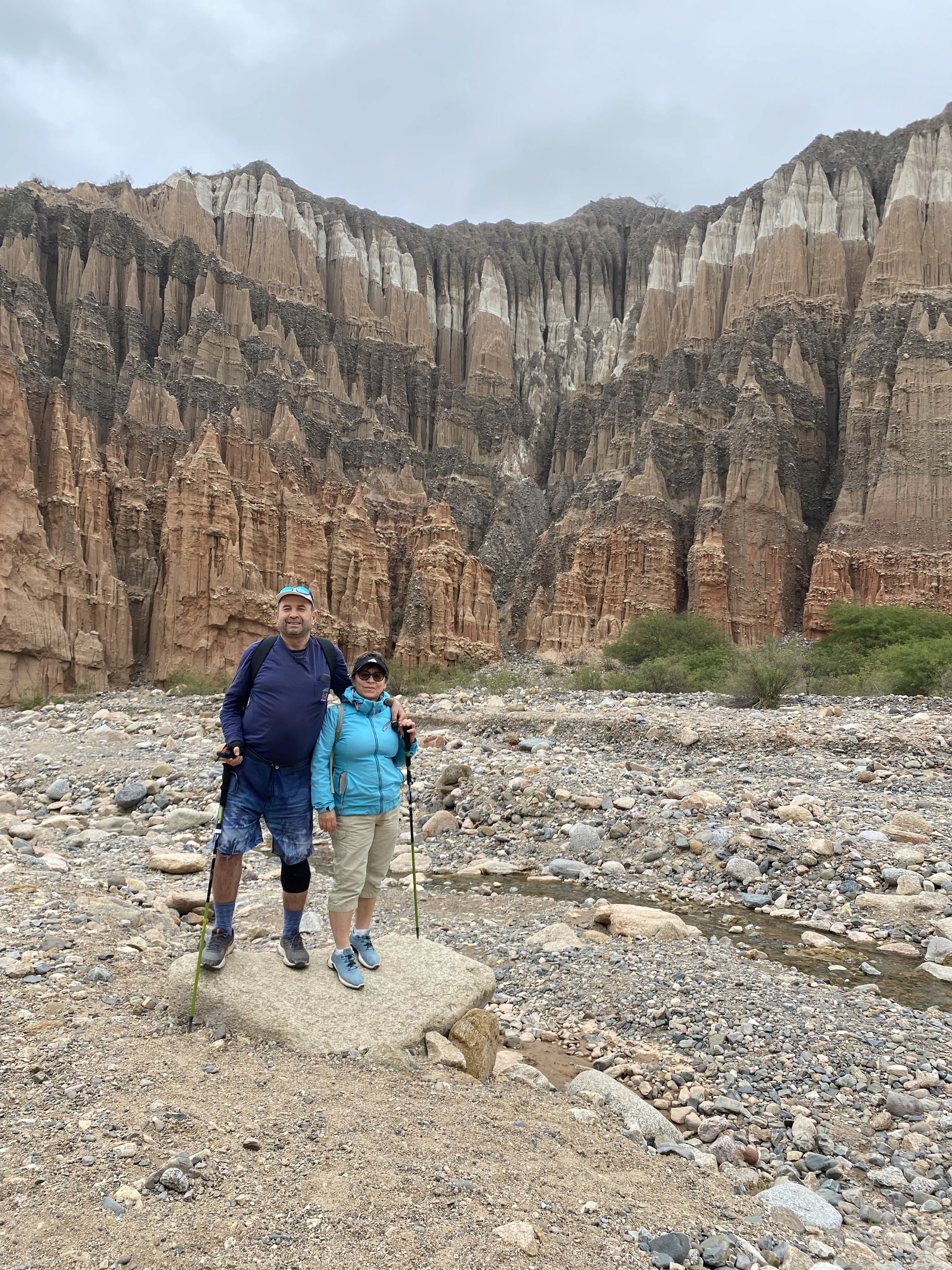 Mujer sentada sobre un tronco frente a una cascada doble en un bosque frondoso de Argentina.