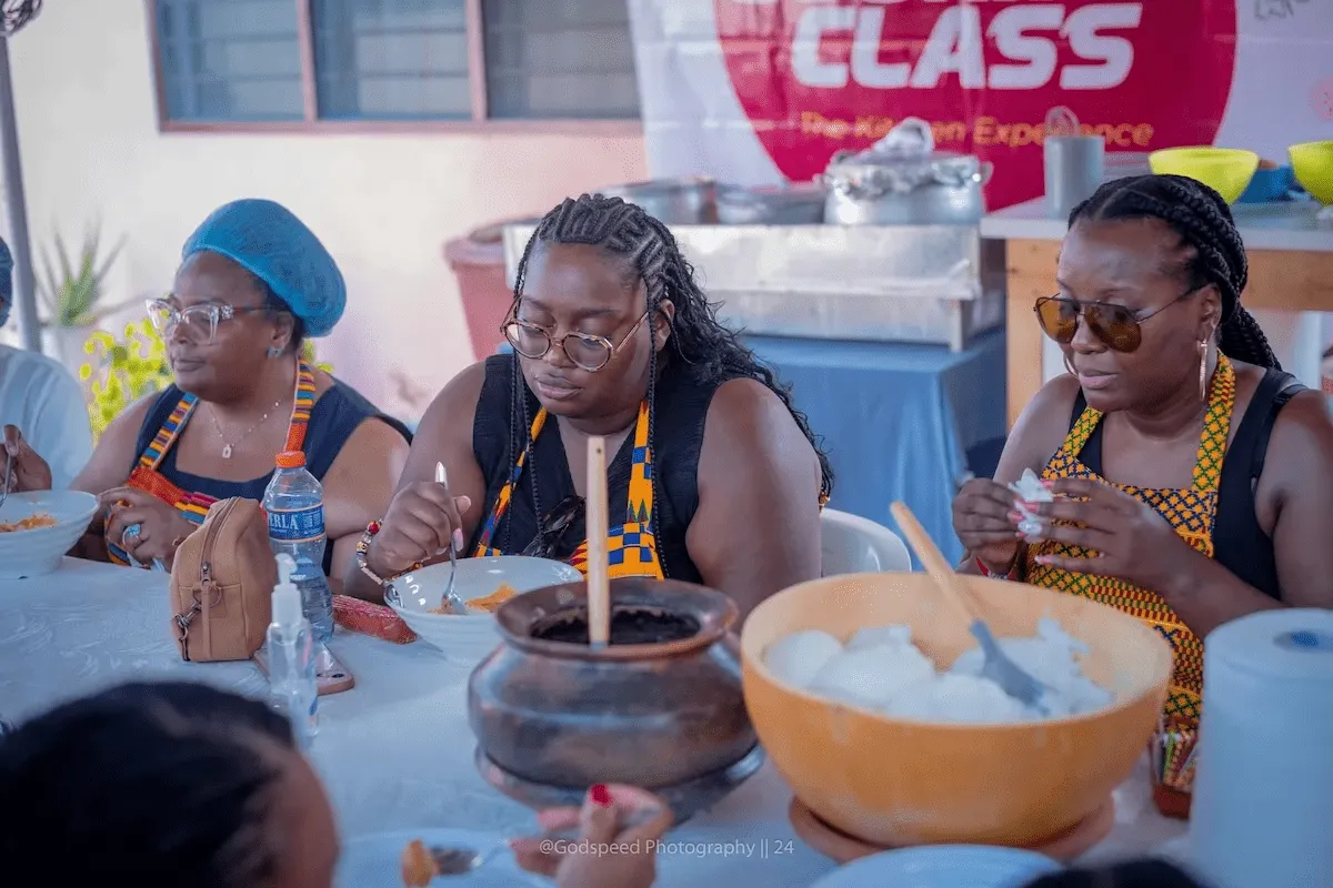 Travelers in kente aprons enjoy a communal meal.