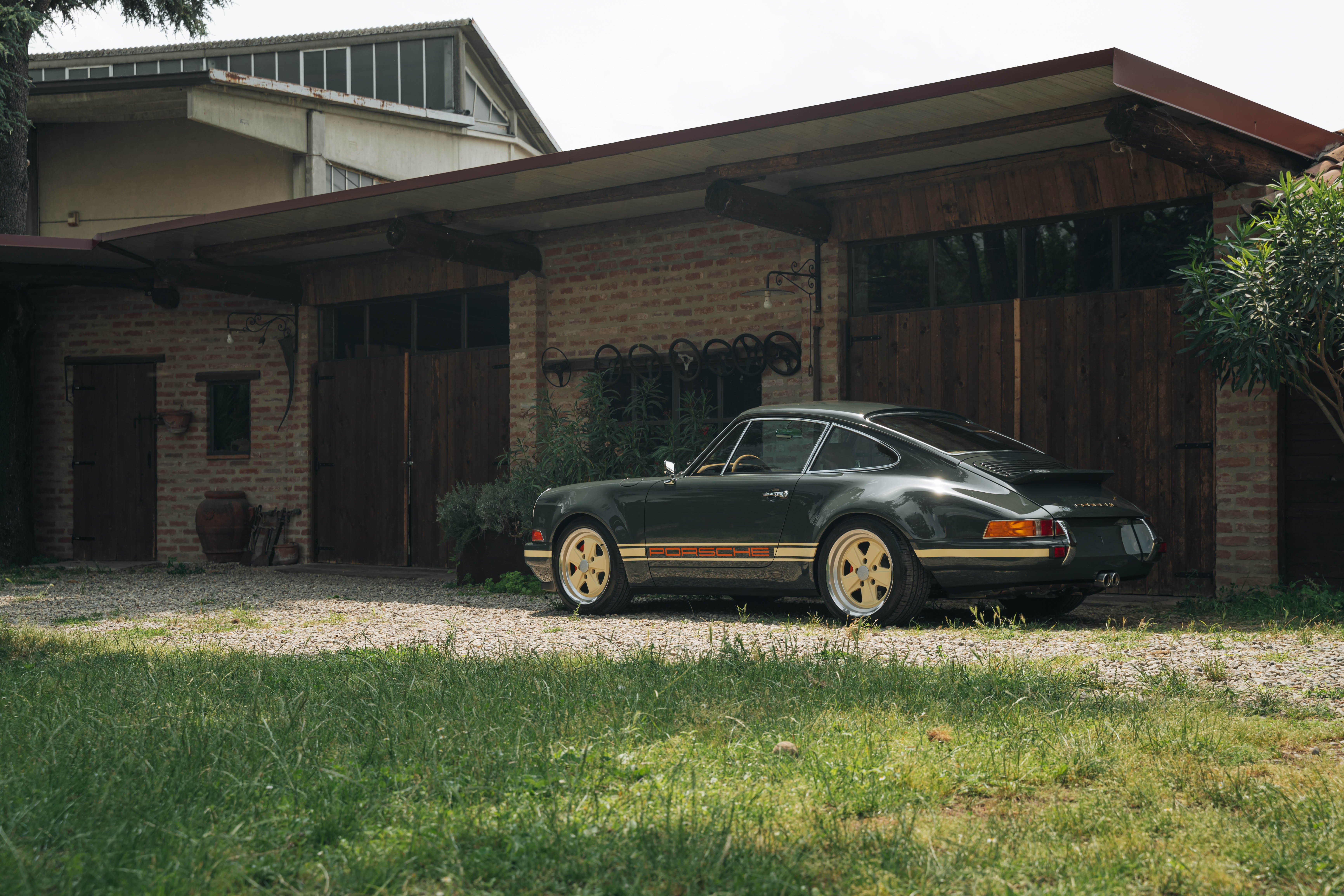 Vista del retro di Porsche Carrera verde di fronte a garage vintage