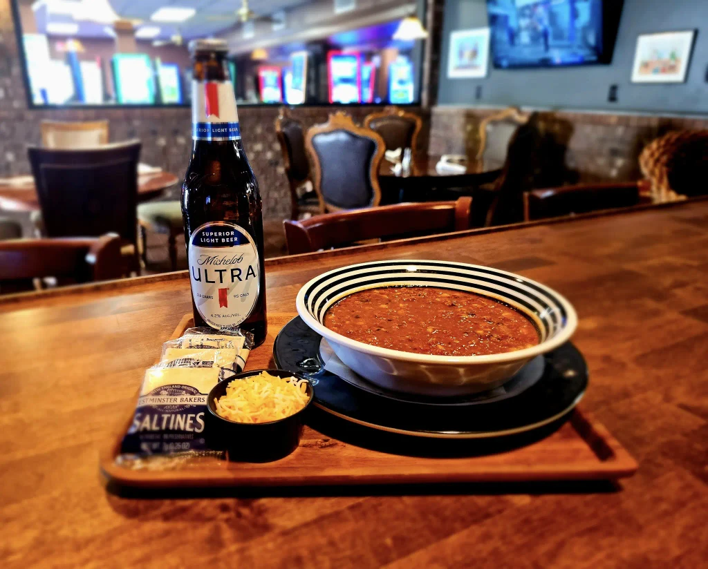 Delicious bowl of chili topped with shredded cheese, accompanied by saltine crackers and a bottle of Michelob Ultra at Dueling Pistols restaurant in Adairville, KY.