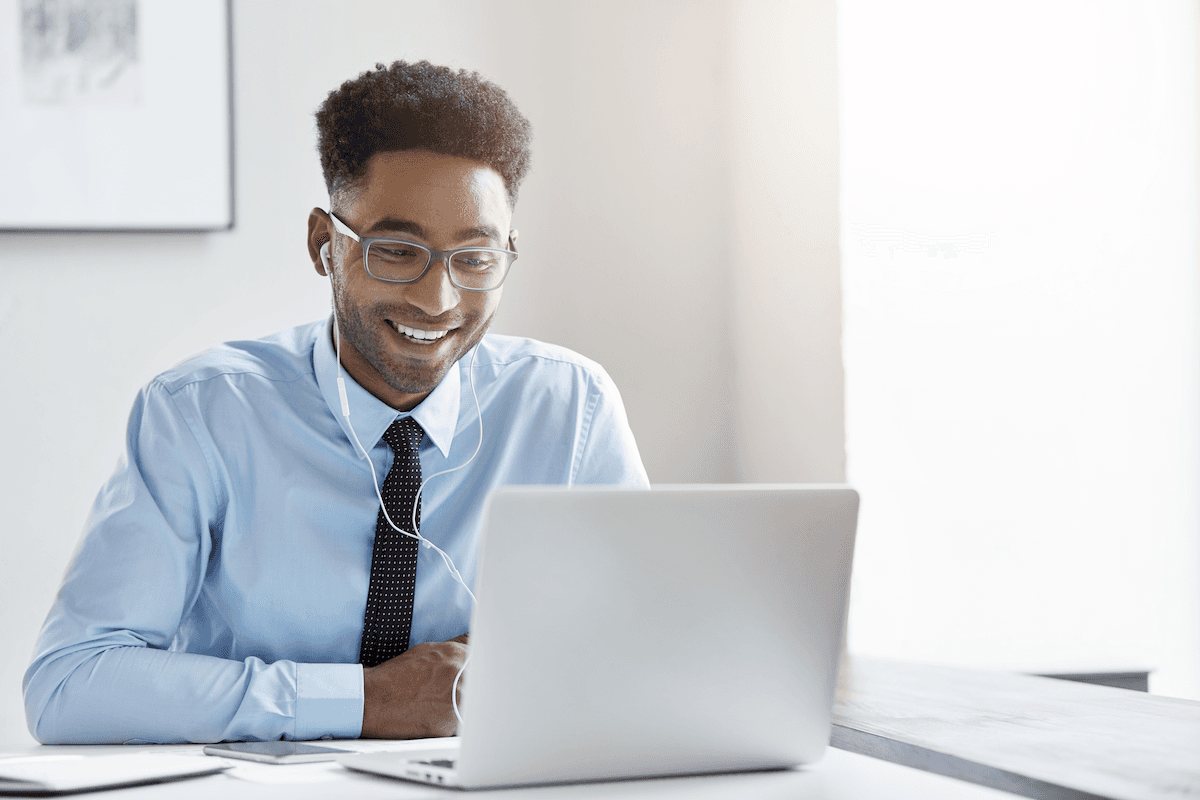 sales methodology: Smiling man wearing earphones and looking at his laptop