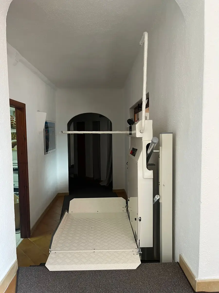 Liftak incline platform stairlift installed indoors in a hallway, with platform extended and ramp lowered ready for wheelchair access