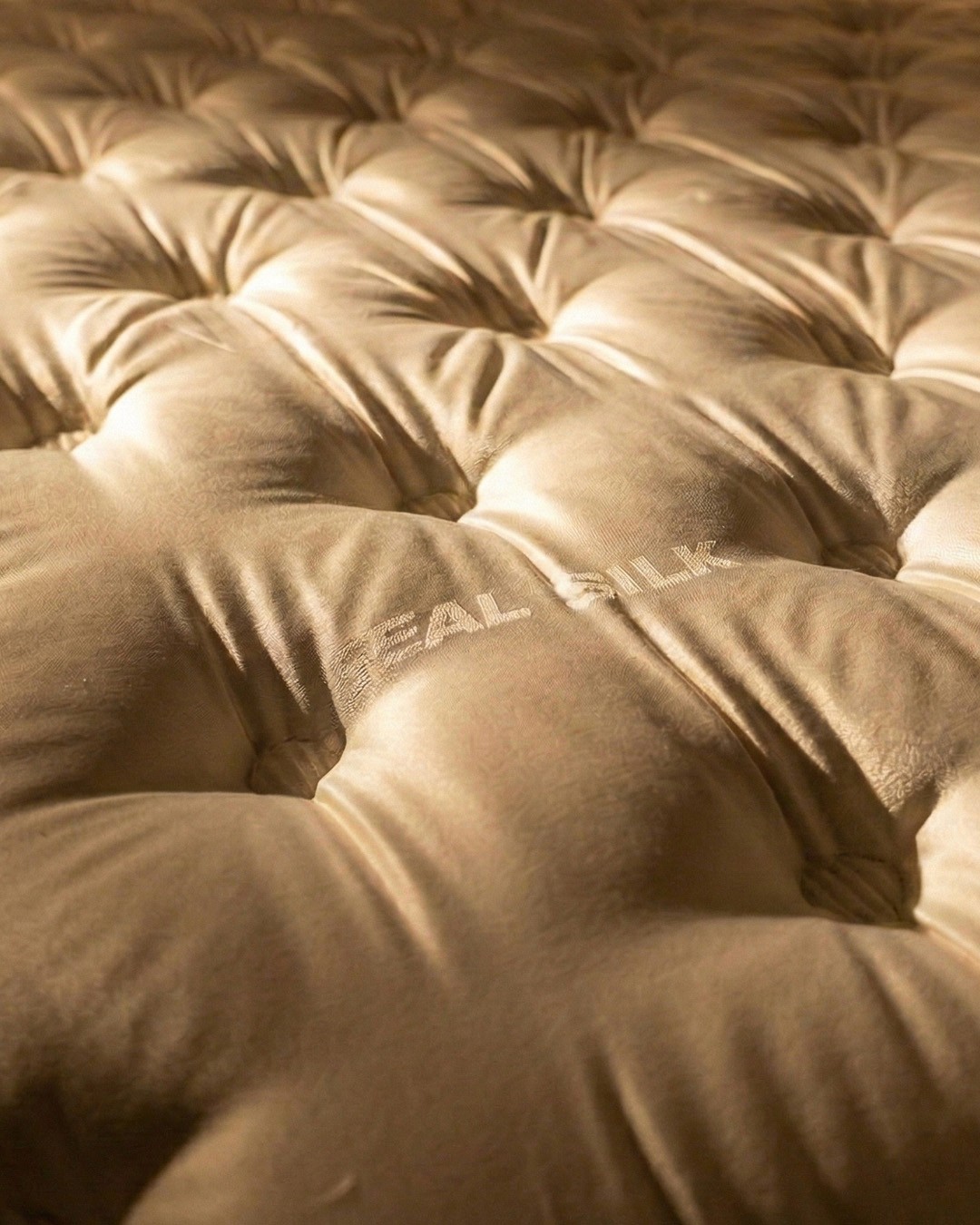 Minimalist beige bedroom with an open shower area, low platform bed, wooden bench, and soft natural lighting.