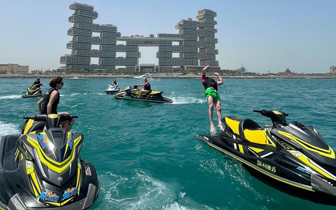 Group of people enjoying jet skiing near a modern architectural backdrop, demonstrating the physical strength and endurance gained from this fun water sport