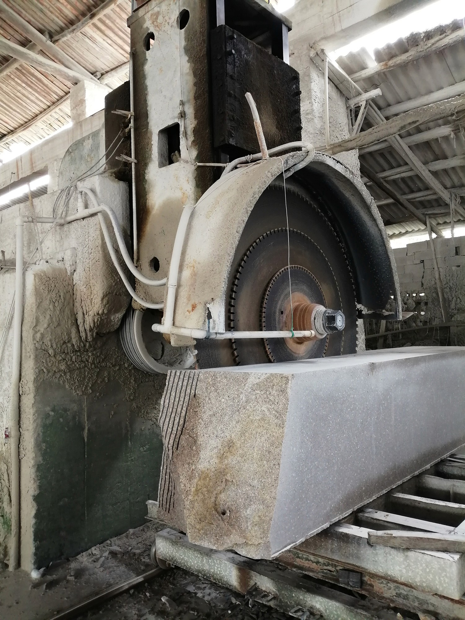 Close-up of a large cutting blade in action on the Single Column Auto Cutting Machine, demonstrating precise and efficient cutting of a stone block.