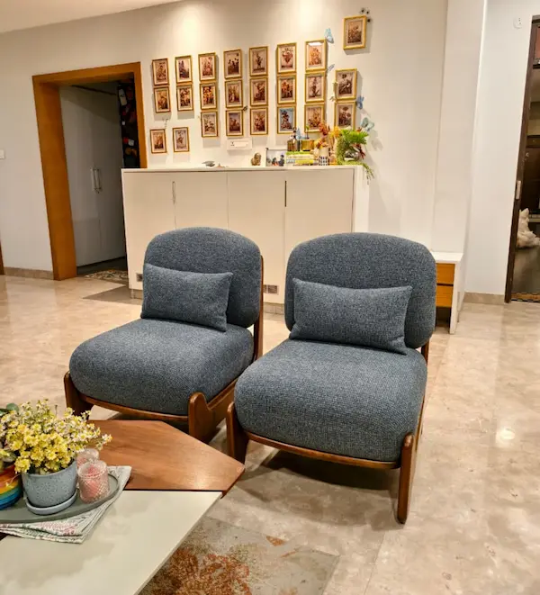 Pair of lounge chairs with rounded backs, wooden frames, and matching lumbar cushions