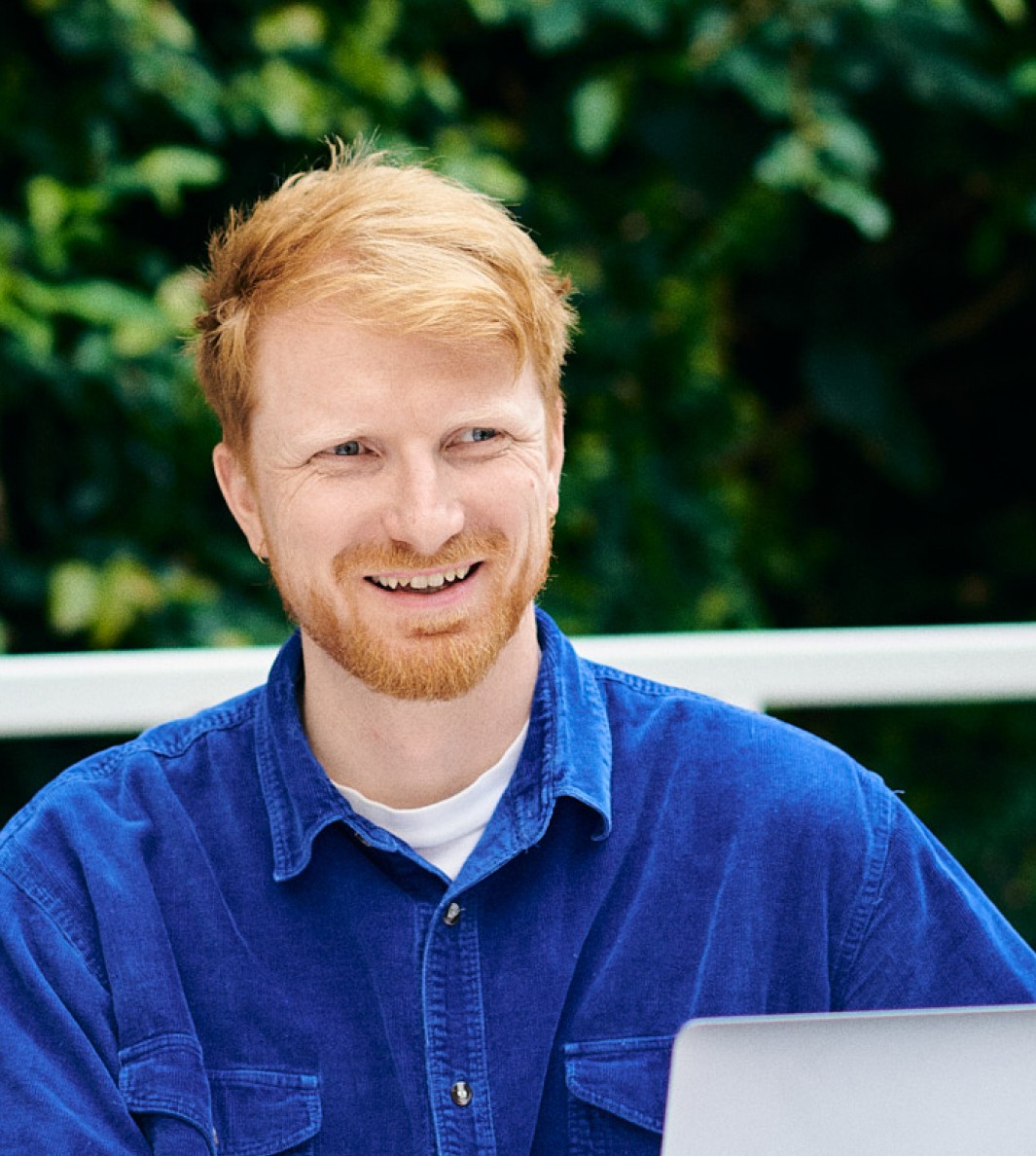 Portrait of Anders Bakken in a bright blue shirt, smiling while consulting a client on design.